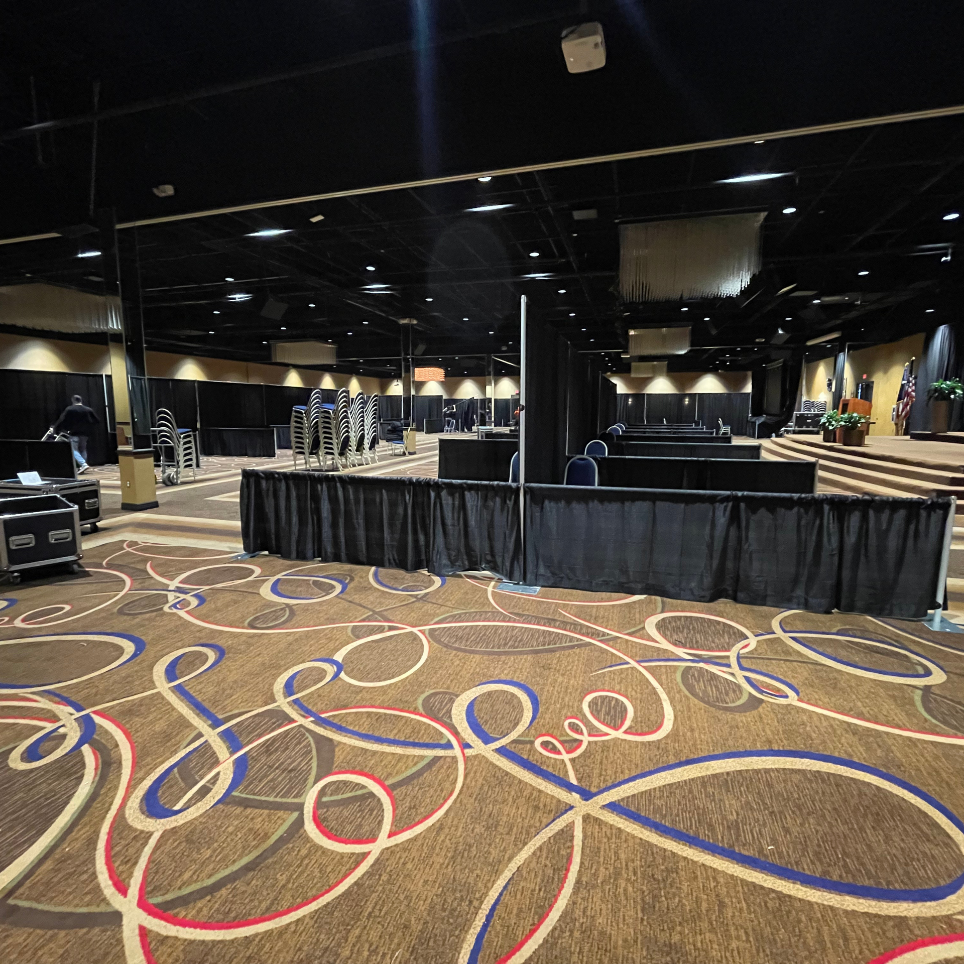 Large empty event hall with black drapery and patterned carpet.
