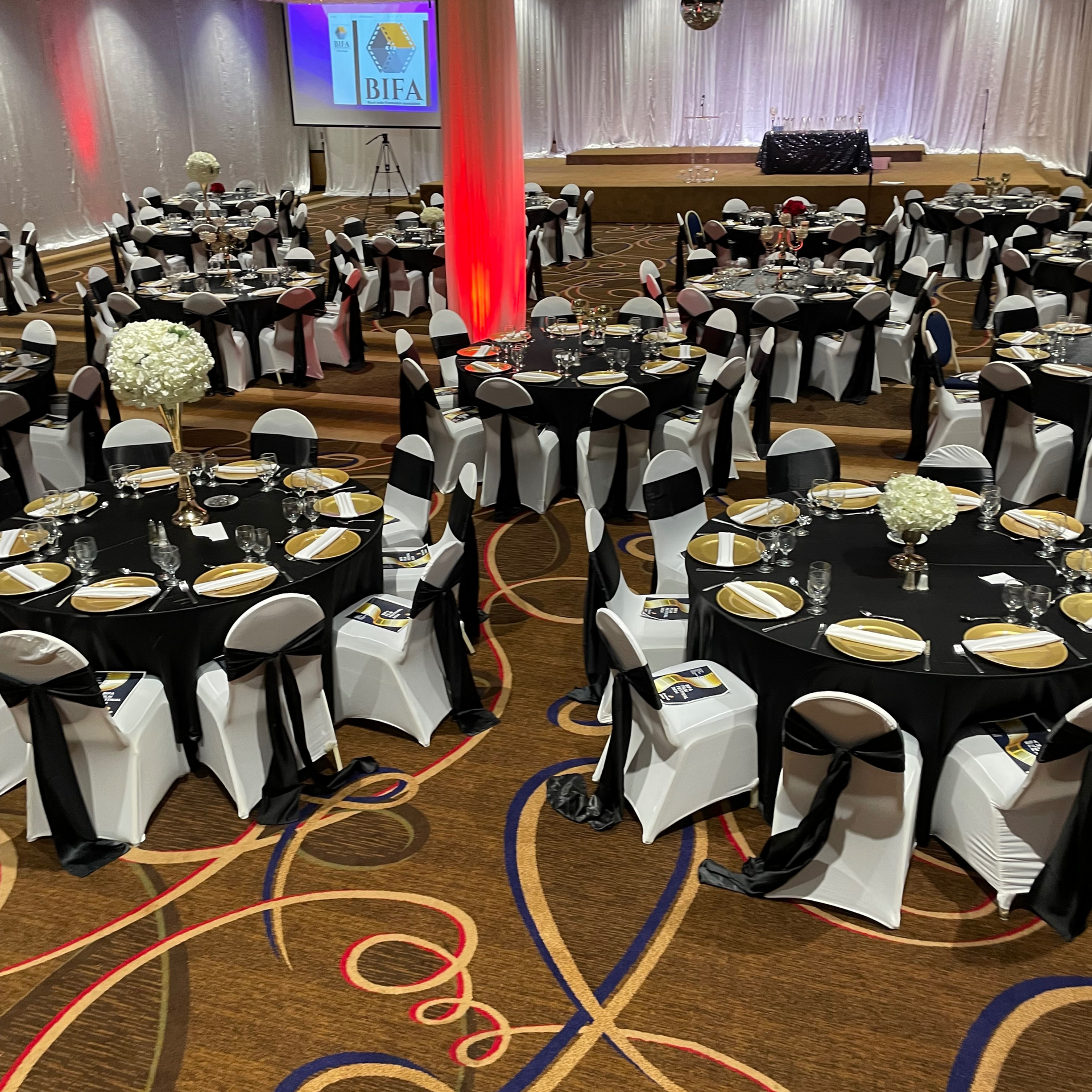 A large room with tables and chairs set up for a wedding reception