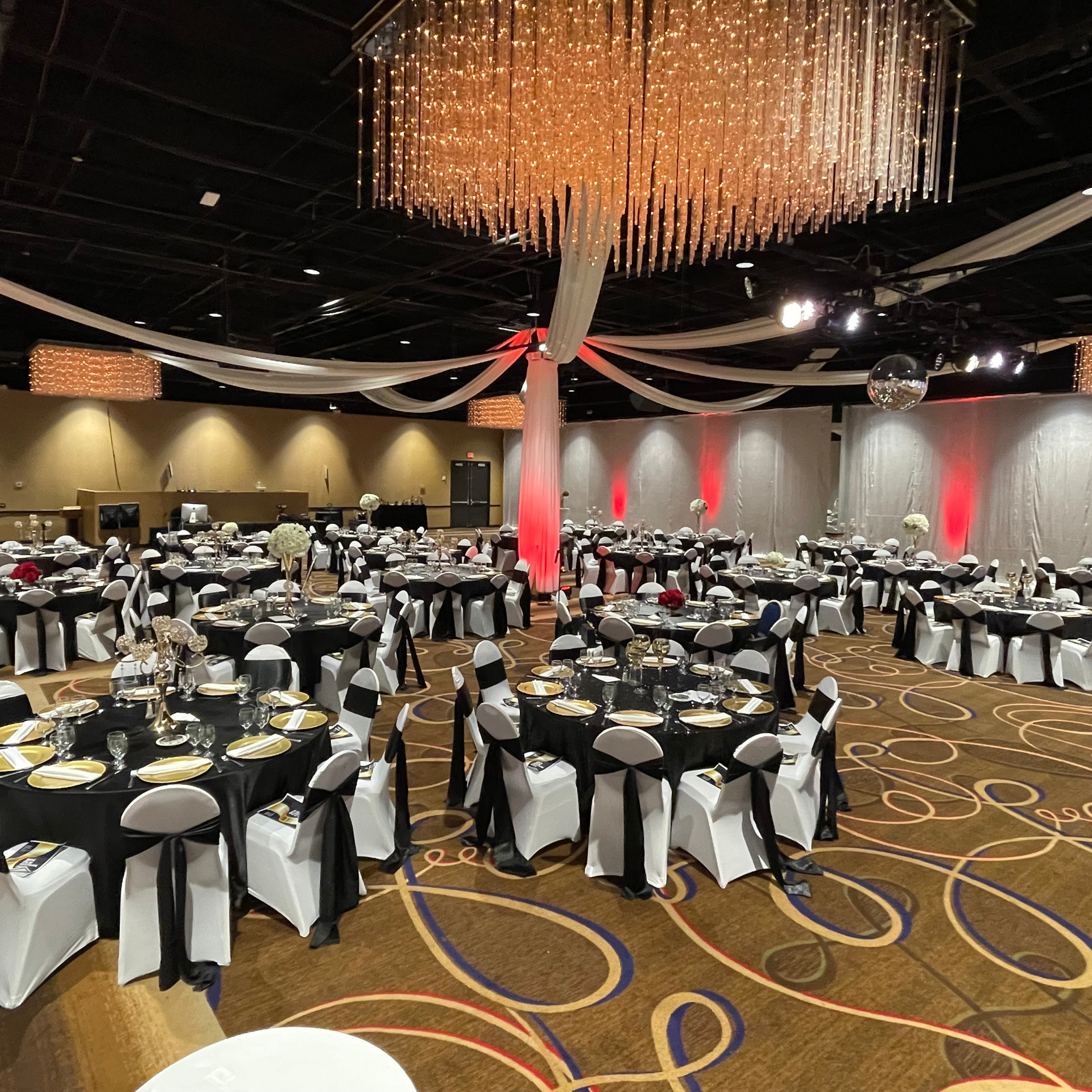 A large room with tables and chairs set up for a wedding reception