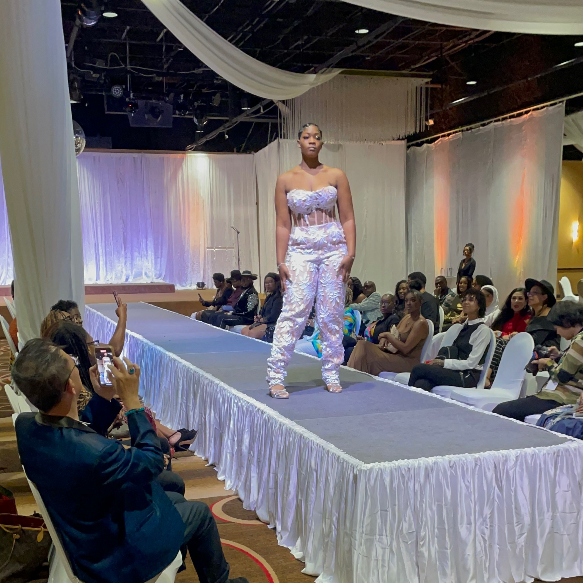 A woman is walking down a runway at a fashion show