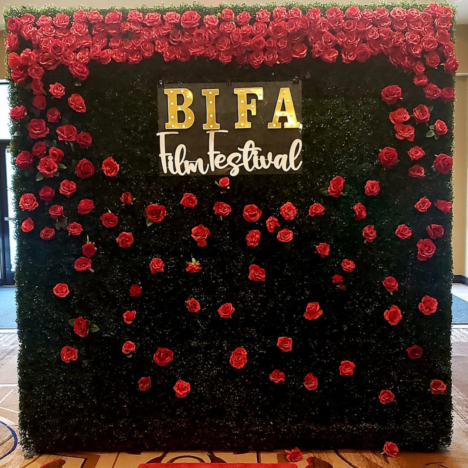 A sign for the bifa film festival is surrounded by red roses