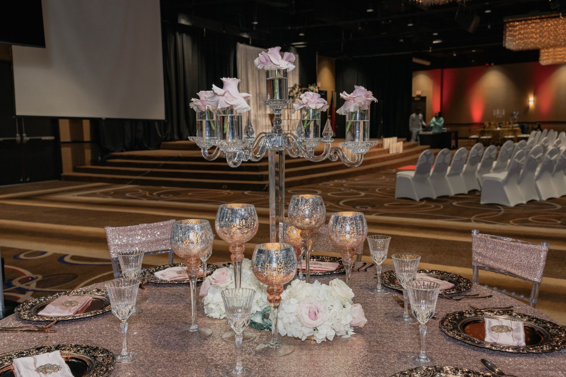 A table set for a wedding reception with a candelabra in the middle.