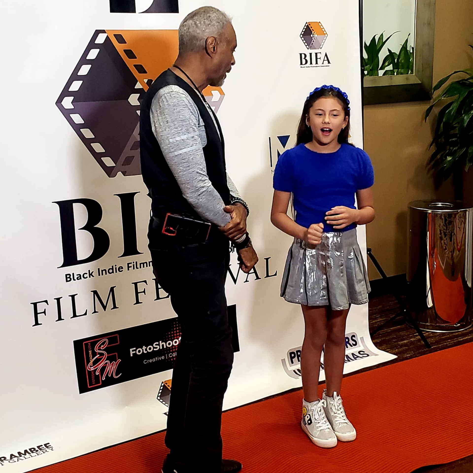 A man and a girl are standing in front of a sign that says bi film festival