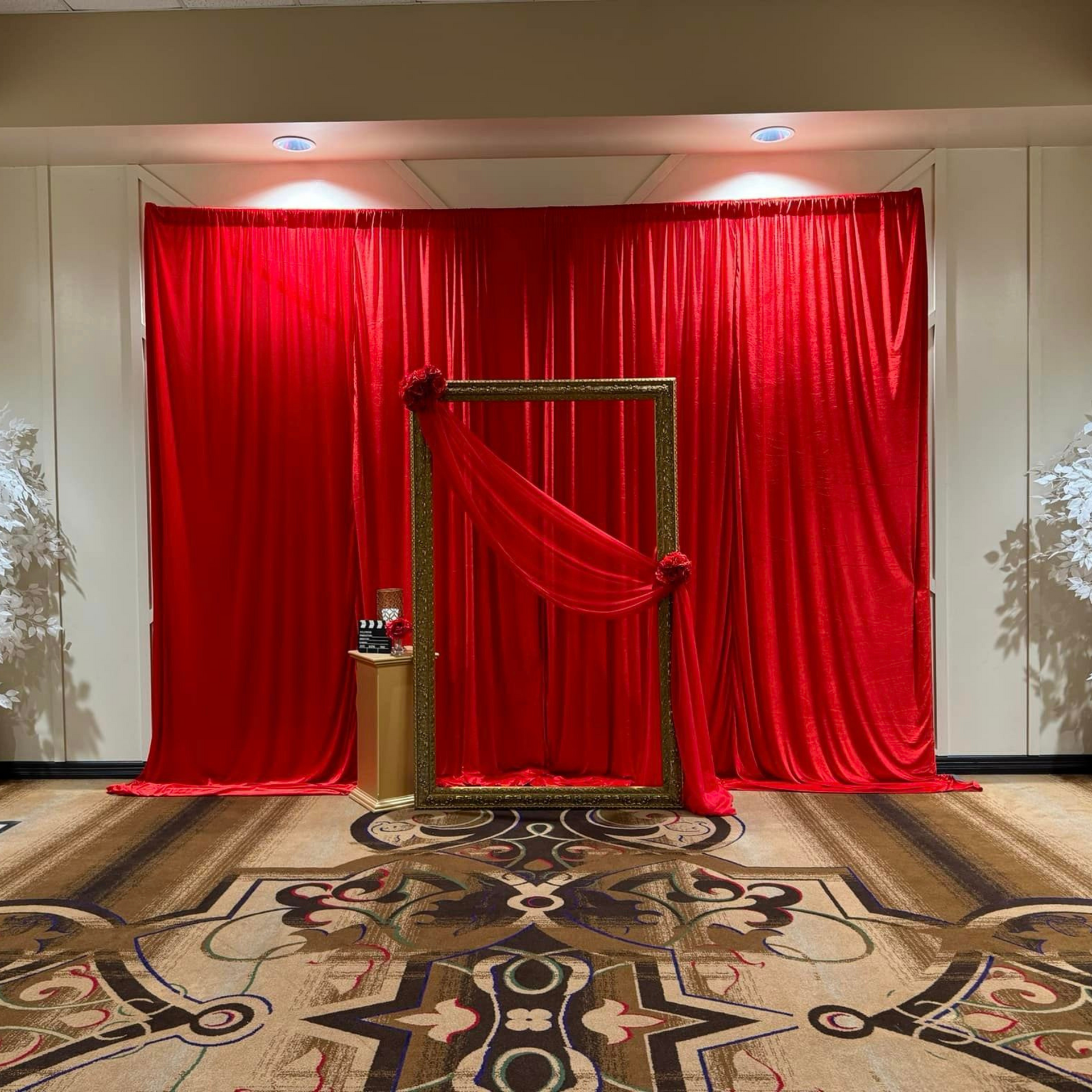 There is a picture frame in front of a red curtain.