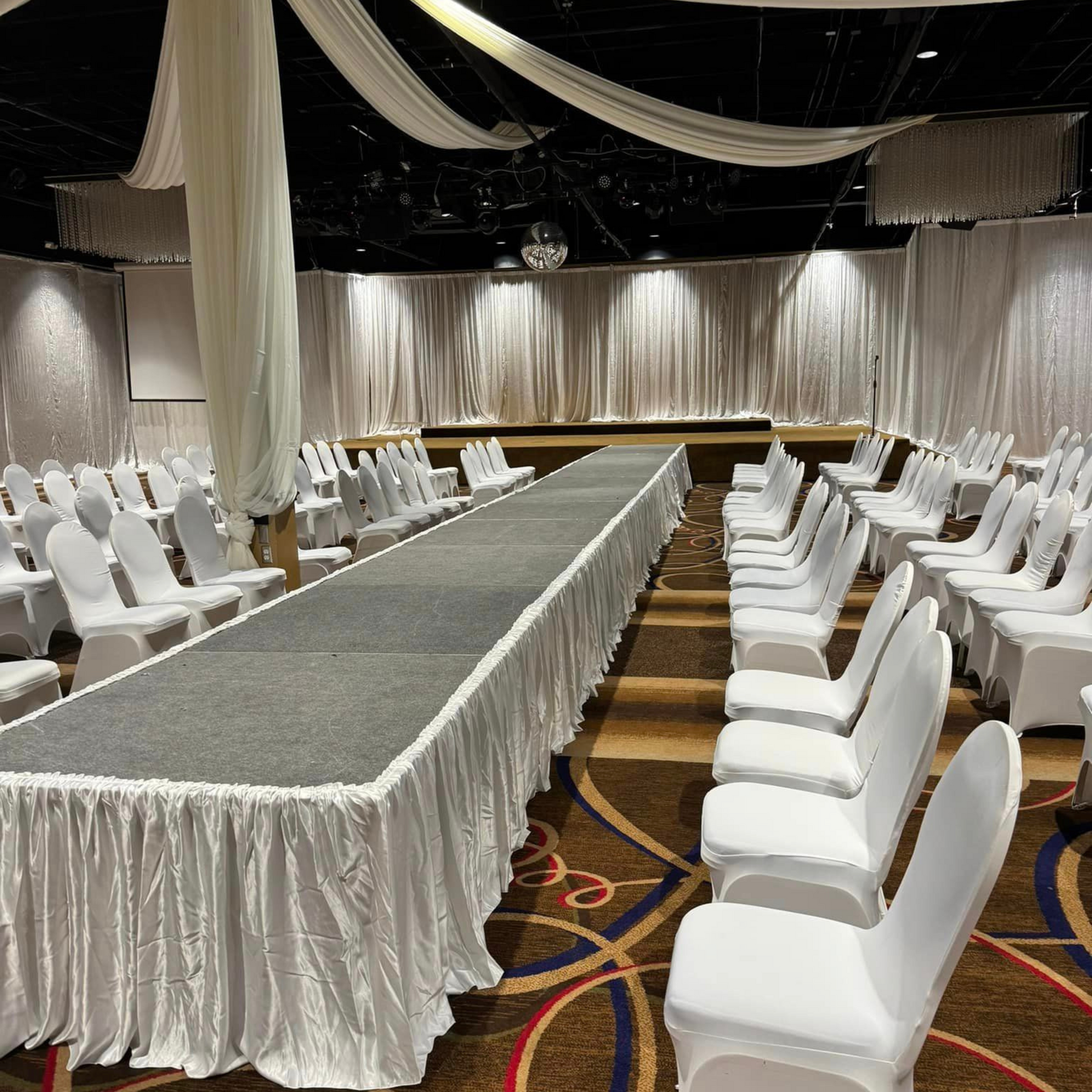 A long runway with white chairs in front of it