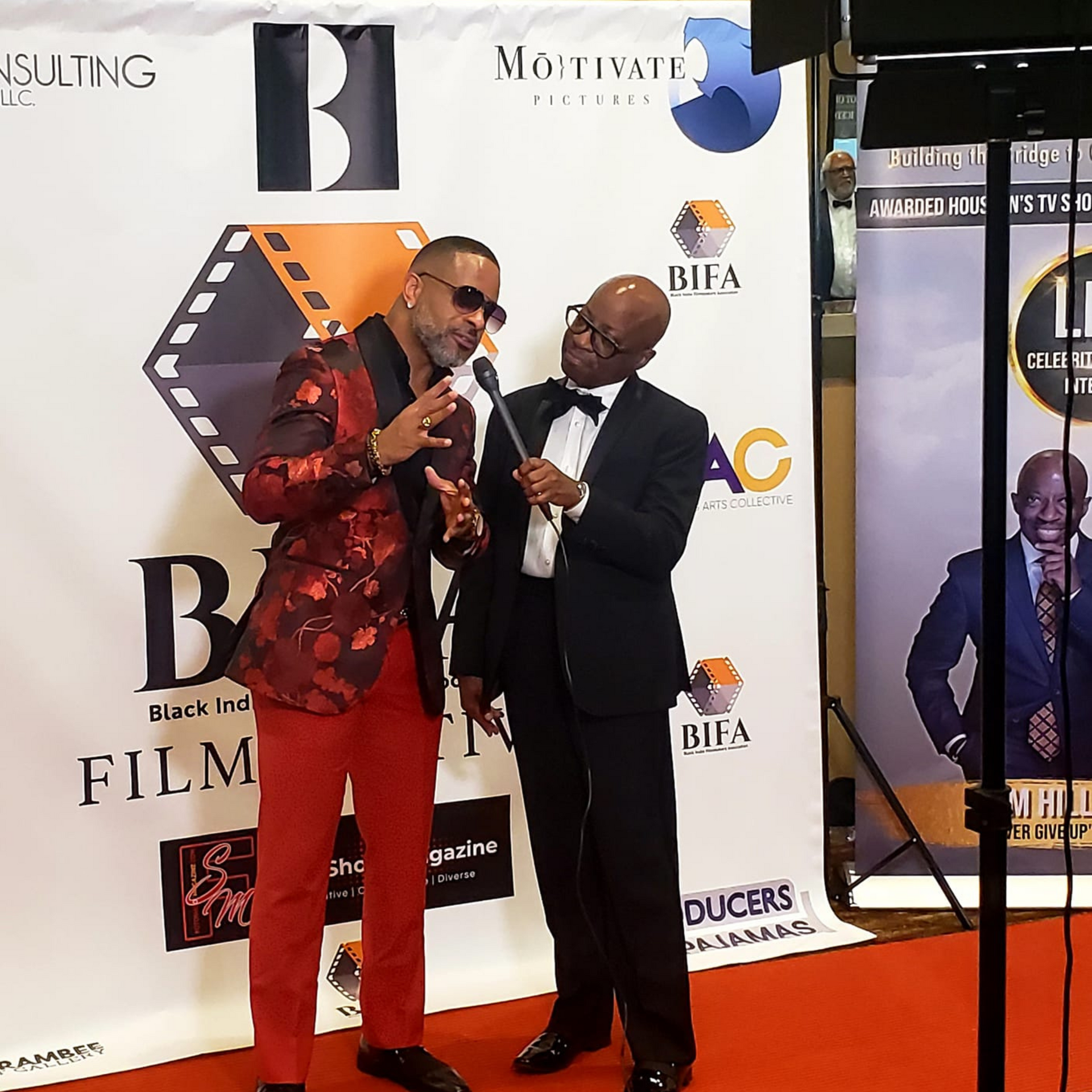 Two men standing in front of a sign that says motivate film