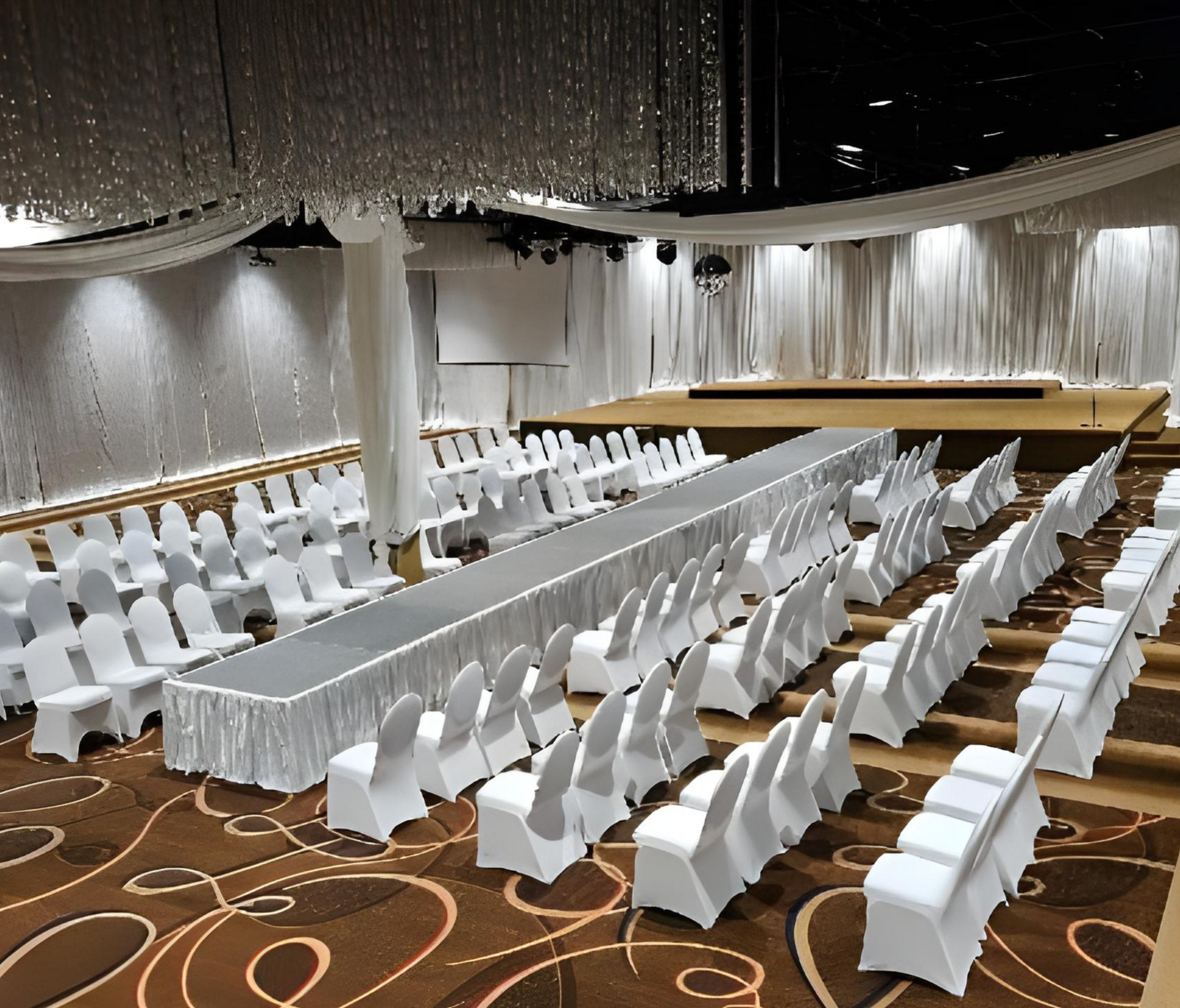 A large room with rows of white chairs and a long runway