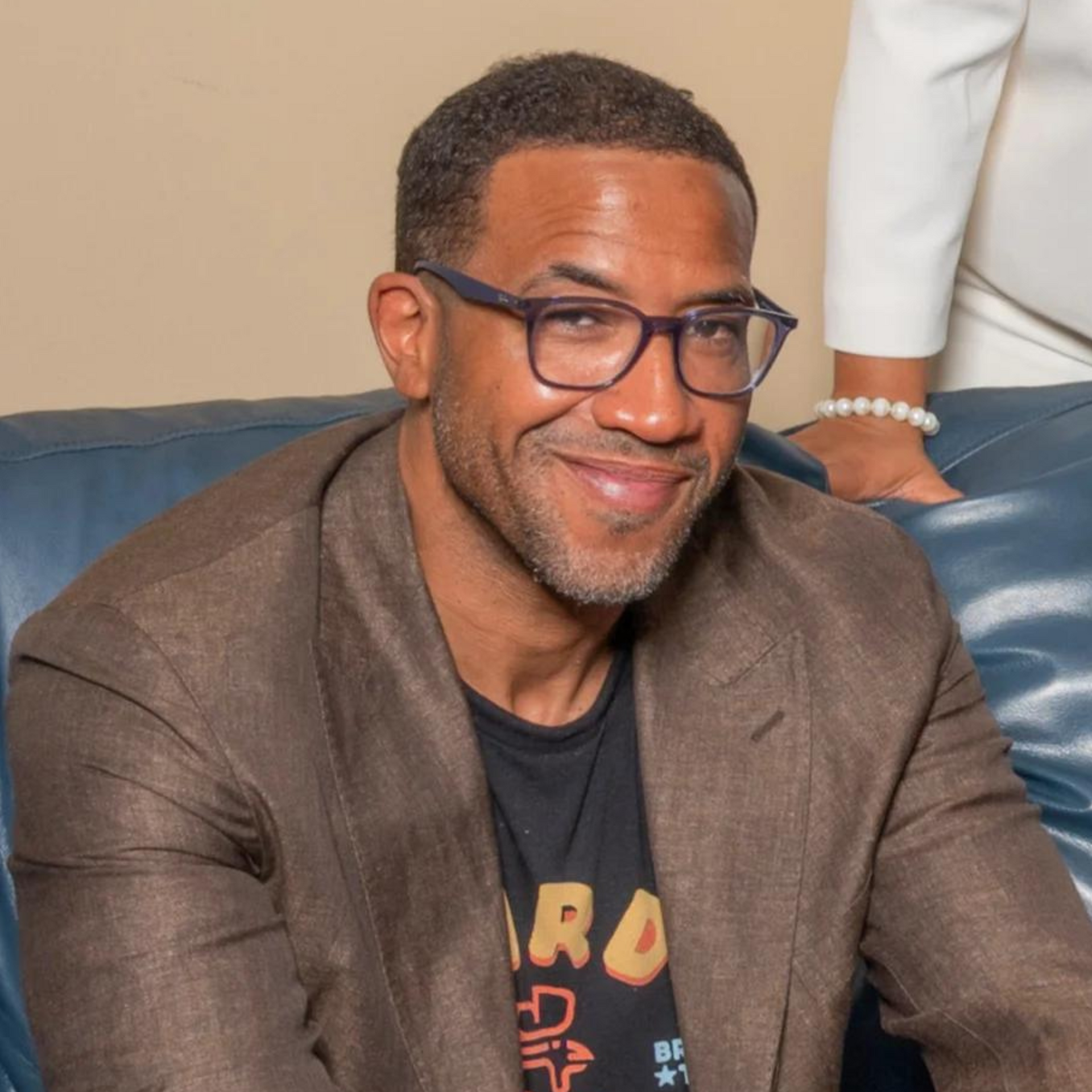 Chef Chris Williams is sitting on a couch, smiling for the camera.