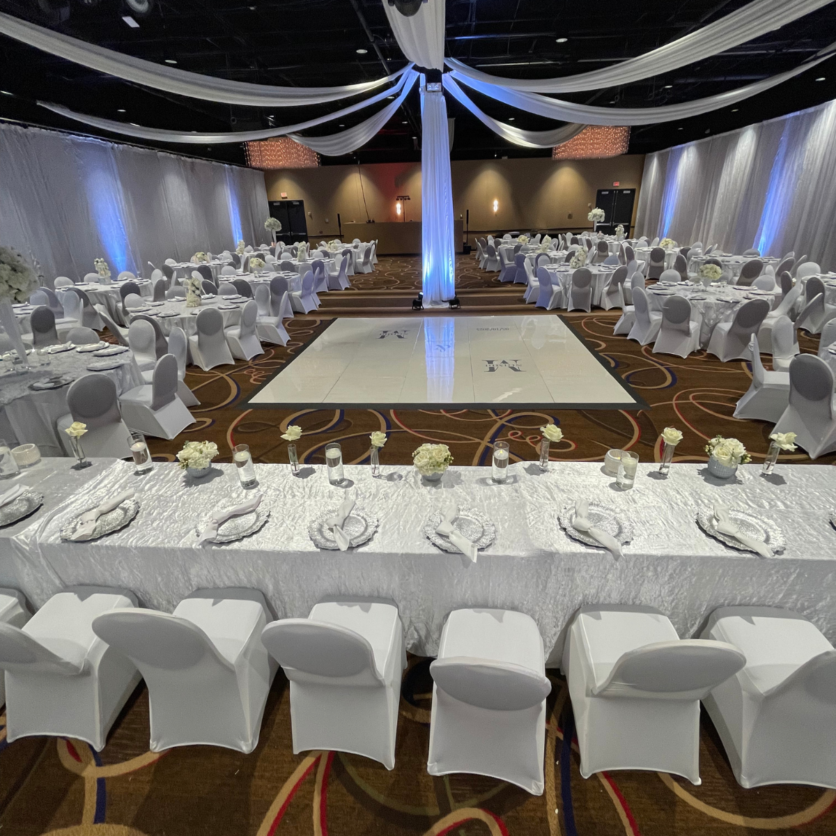 A large room with tables and chairs set up for a wedding reception