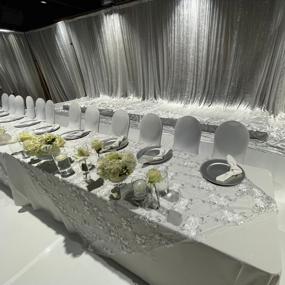 A long table with plates, napkins, and flowers on it.