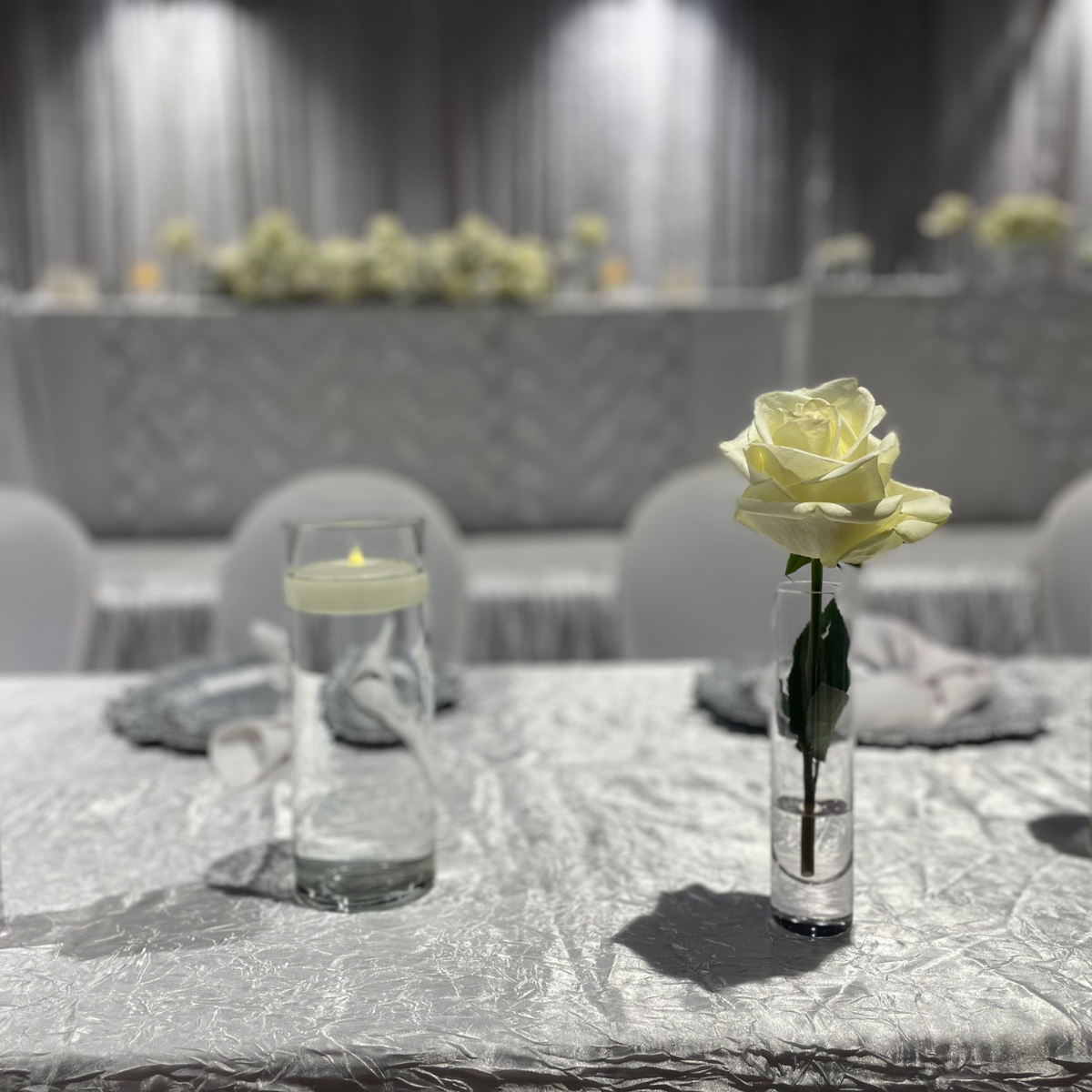 A single white rose in a vase on a table.