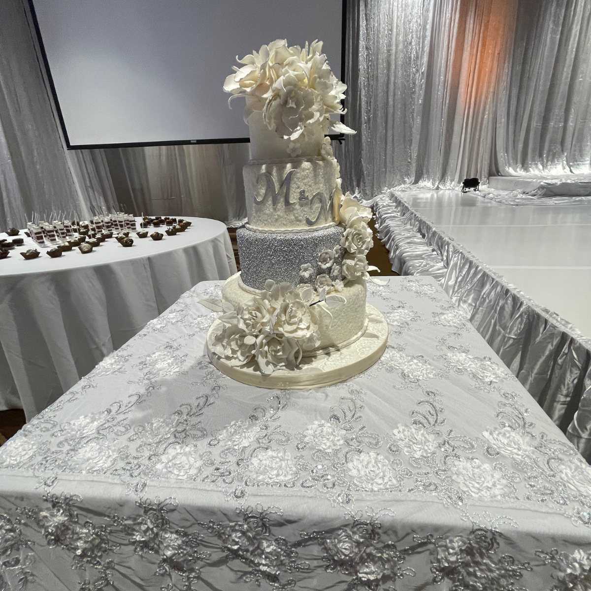 A wedding cake is sitting on top of a white table cloth.