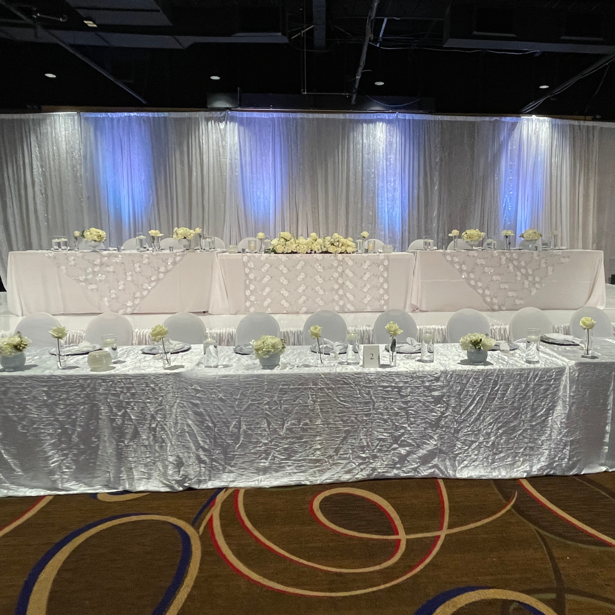 A long white table with flowers and glasses on it