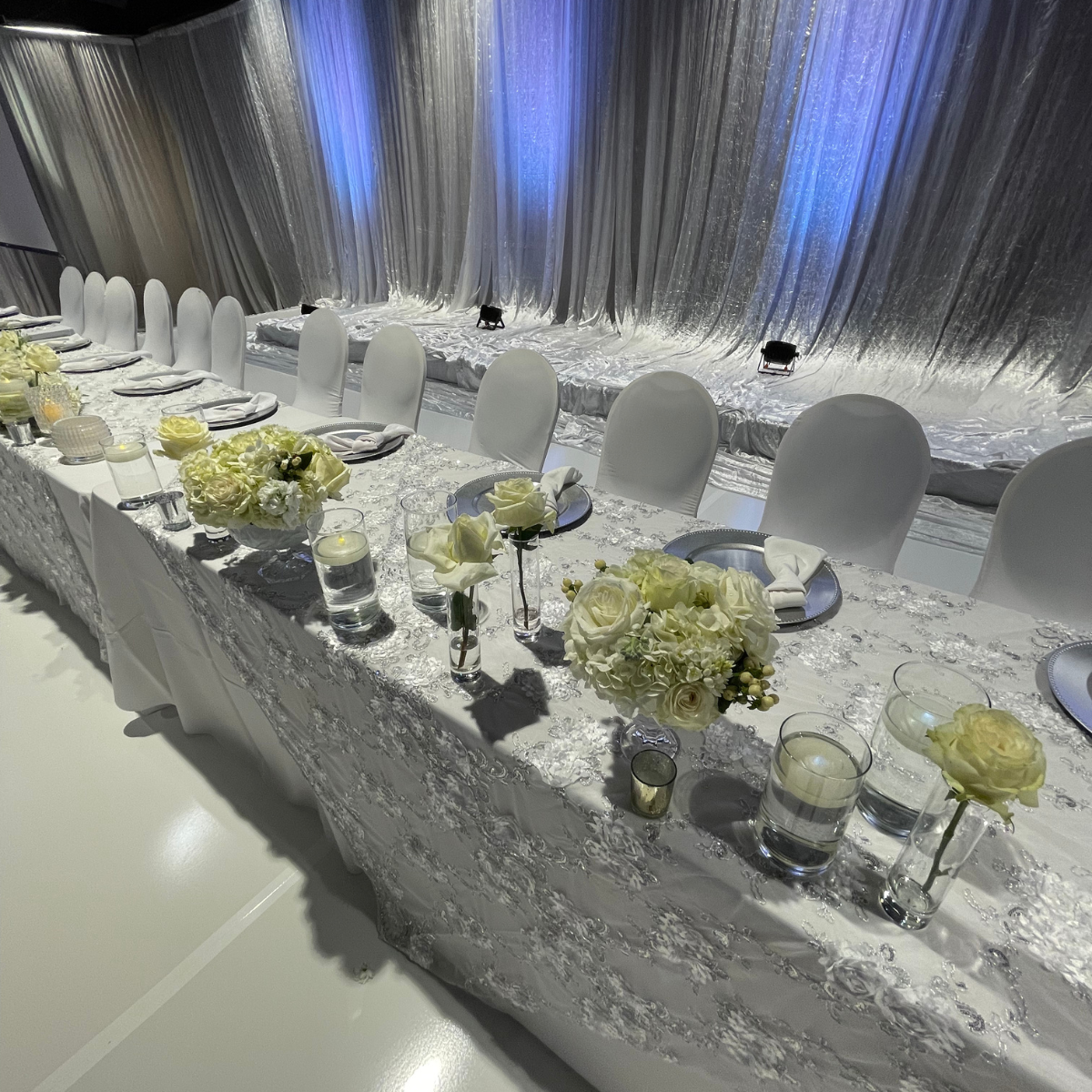 A long white table with flowers and candles on it