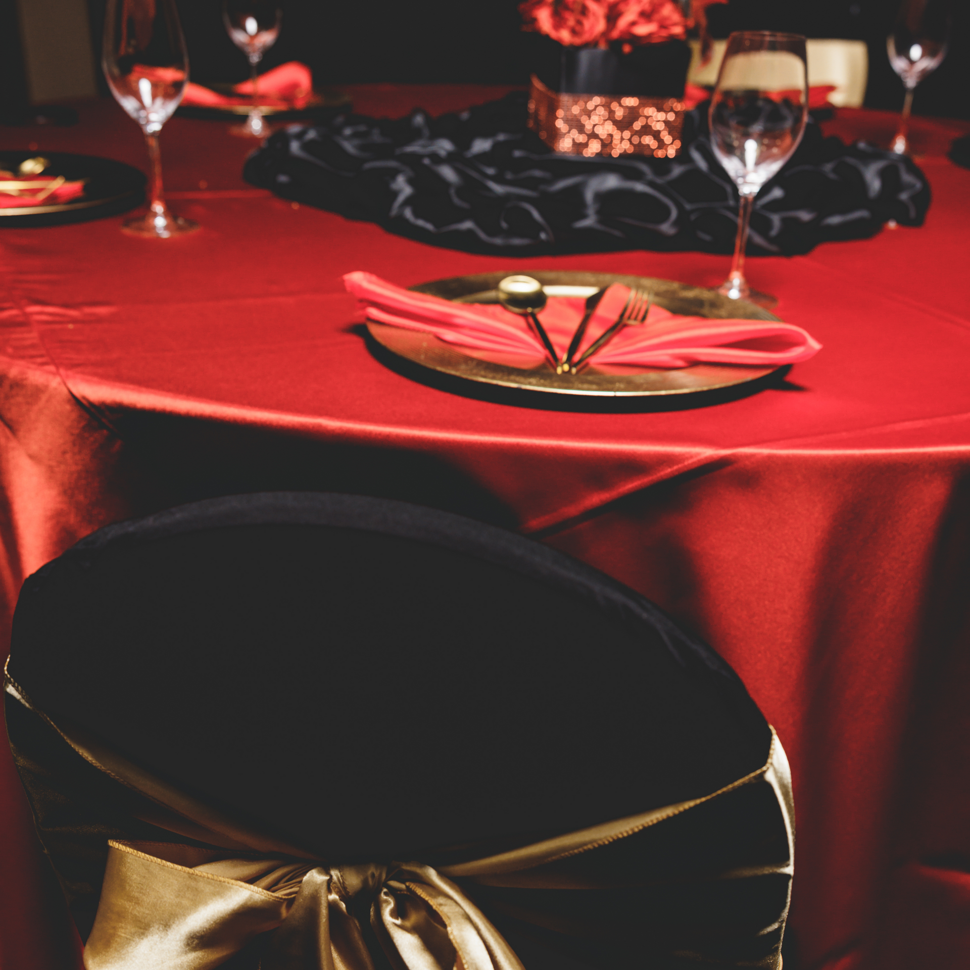 A table with a red table cloth and black chairs