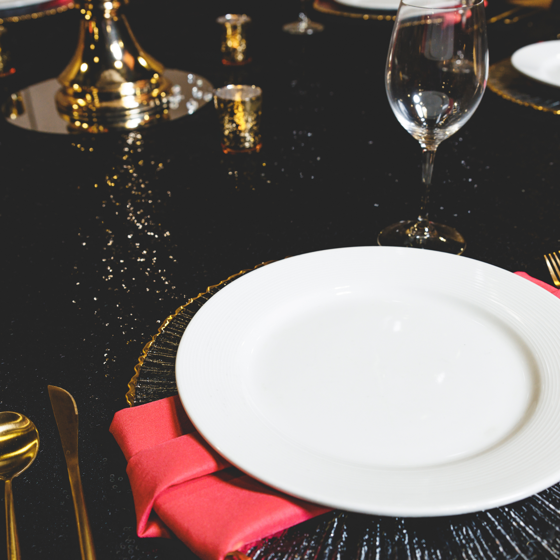 A white plate with a pink napkin on a black table
