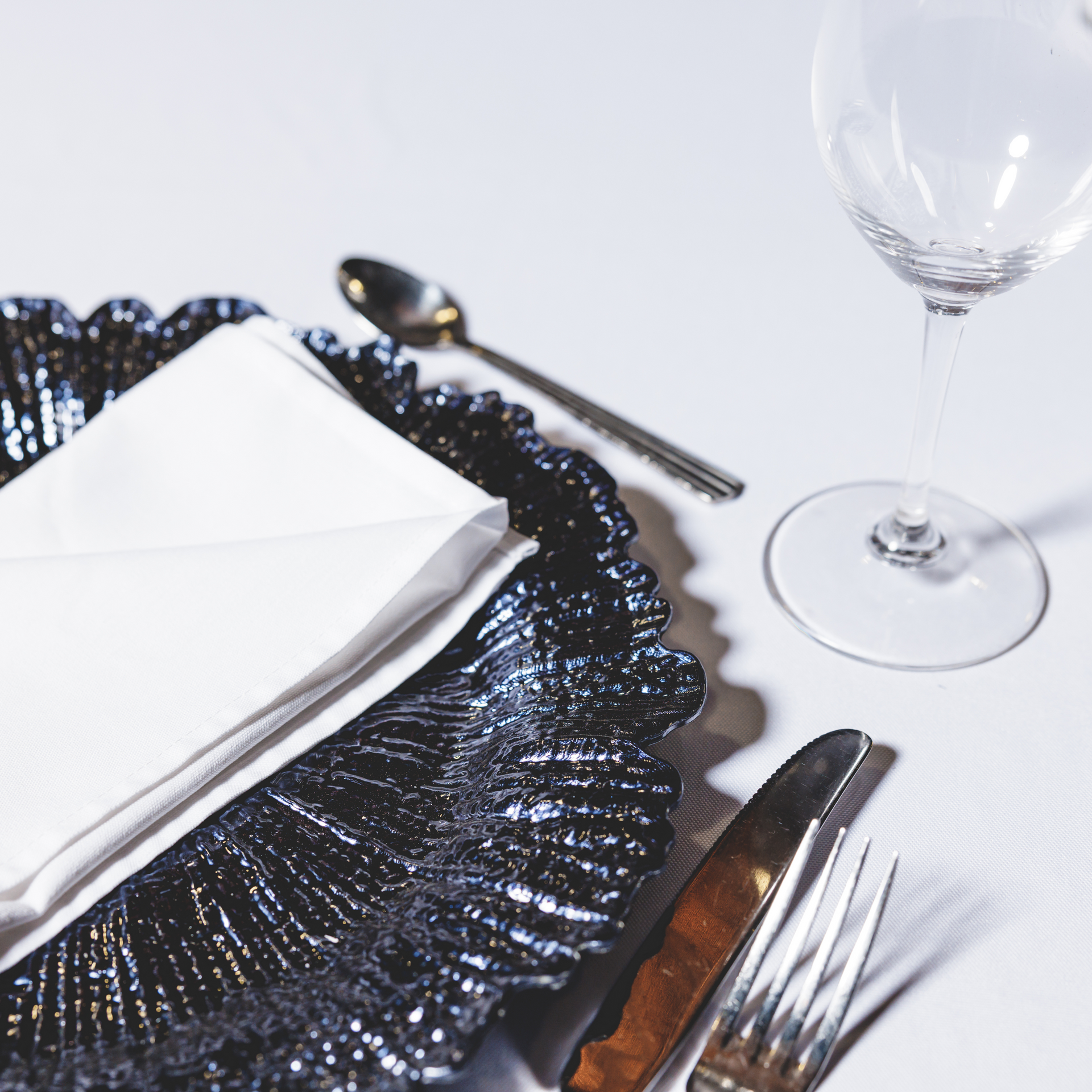 A black plate with a white napkin and silverware on it