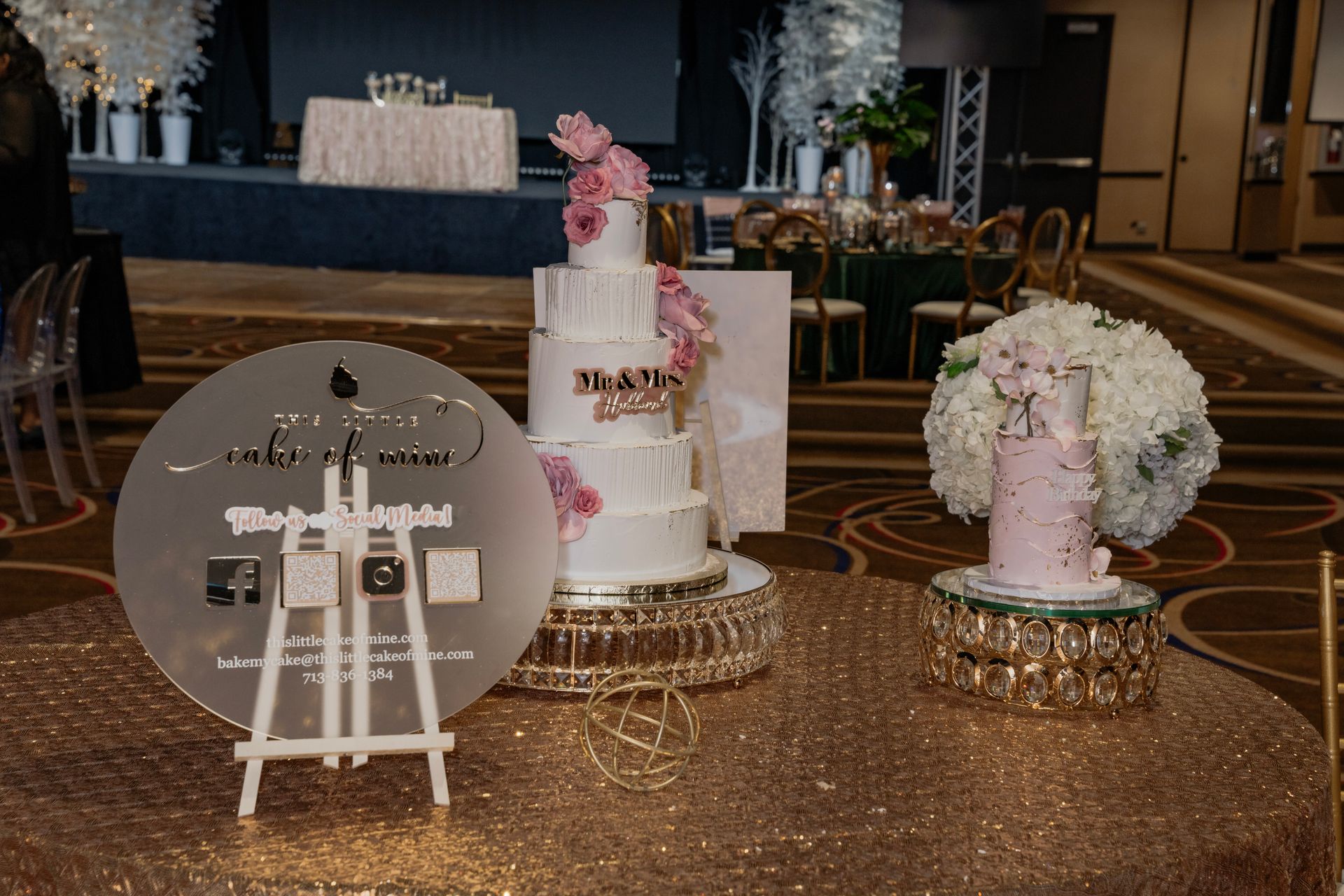 A table with three cakes and a sign on it.