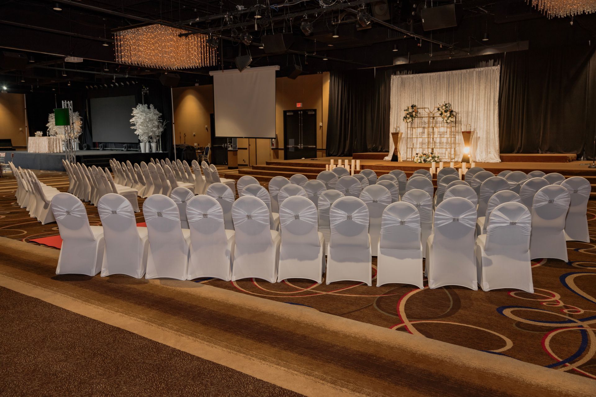 Rows of white chairs are lined up in a large room.