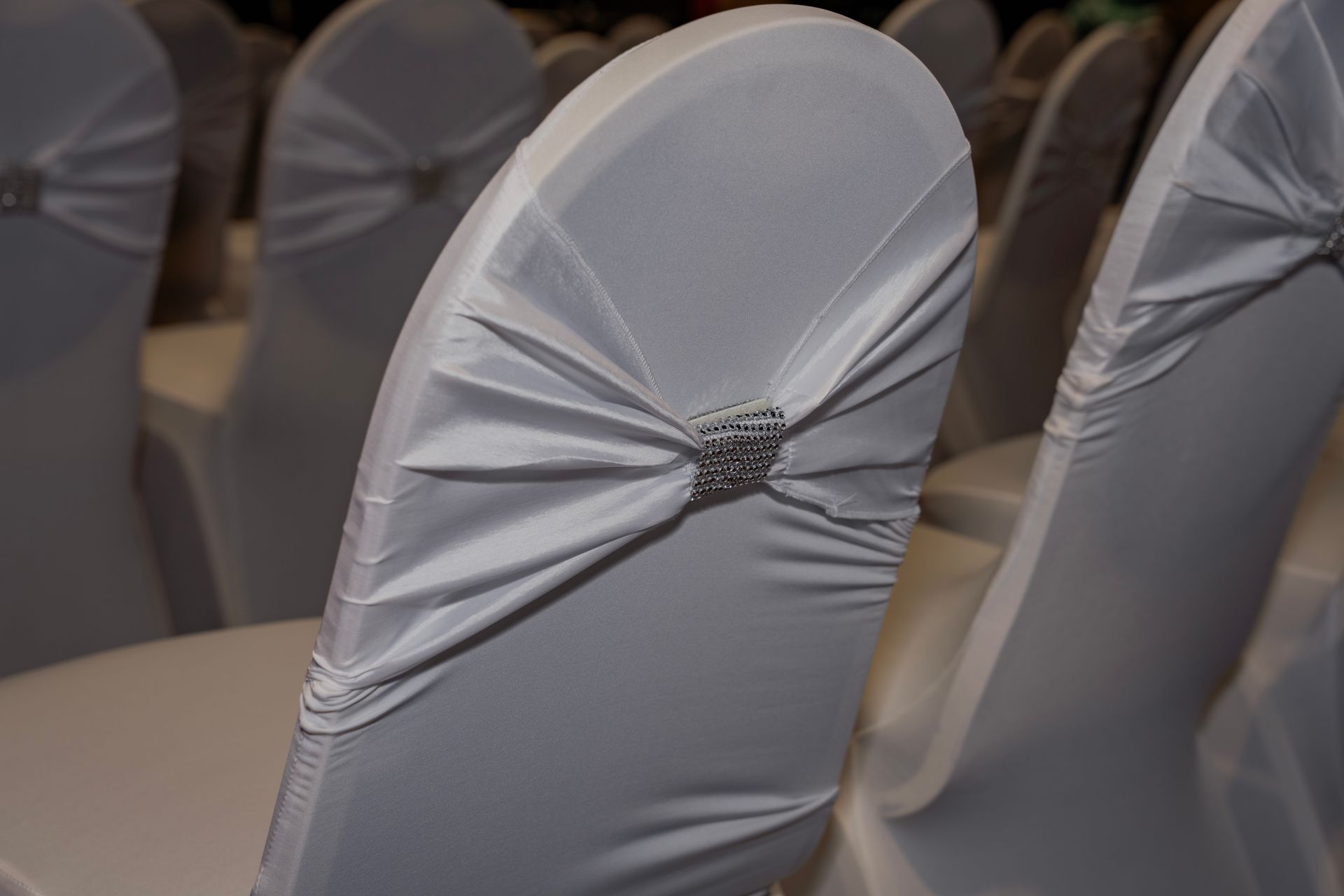 A close-up of a white chair with a bow on the back.