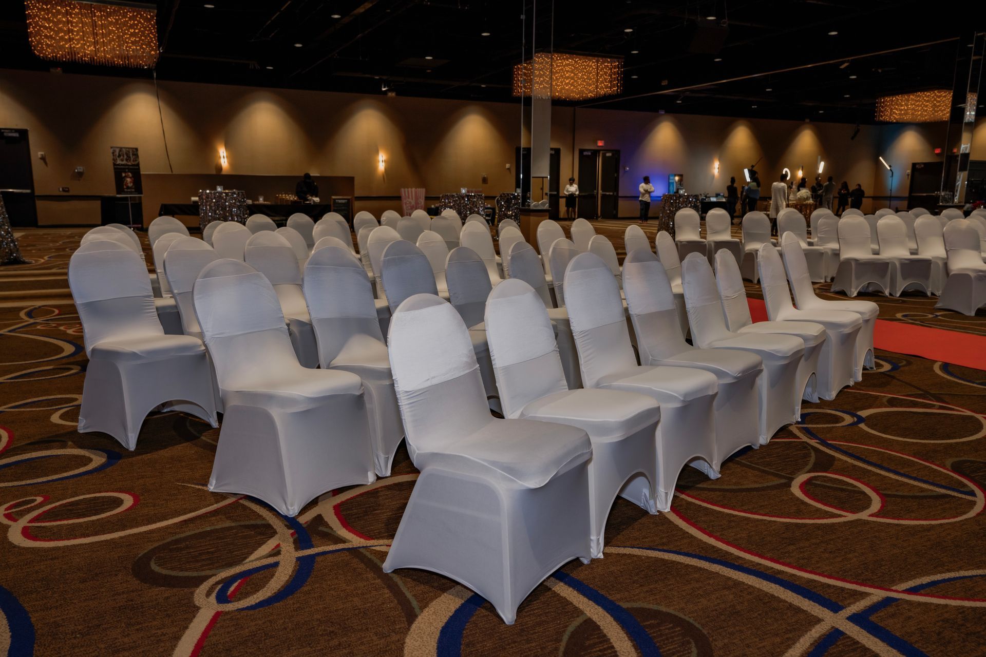 Rows of white chairs are lined up in a large room.