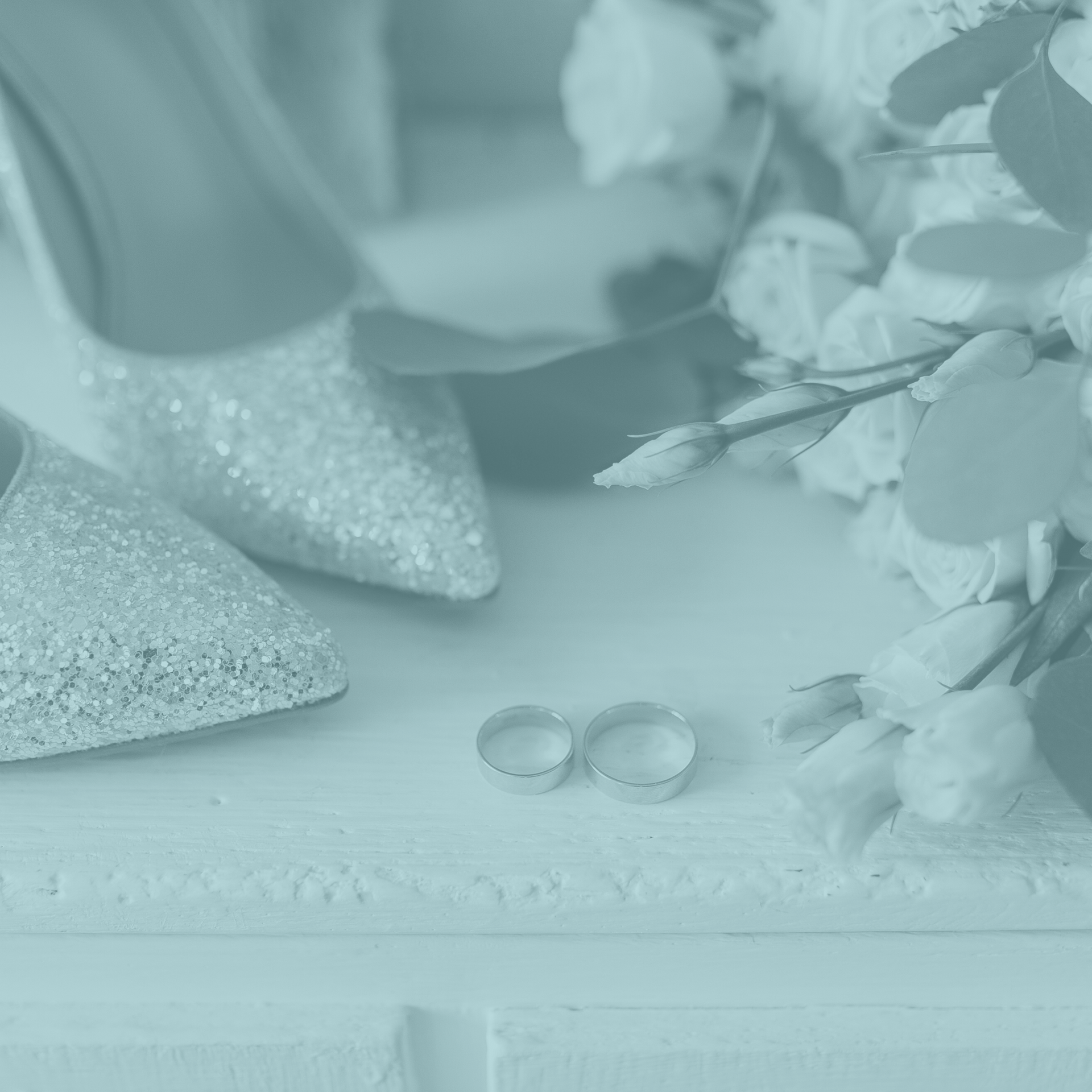 A pair of wedding shoes and wedding rings are on a table next to a bouquet of flowers.