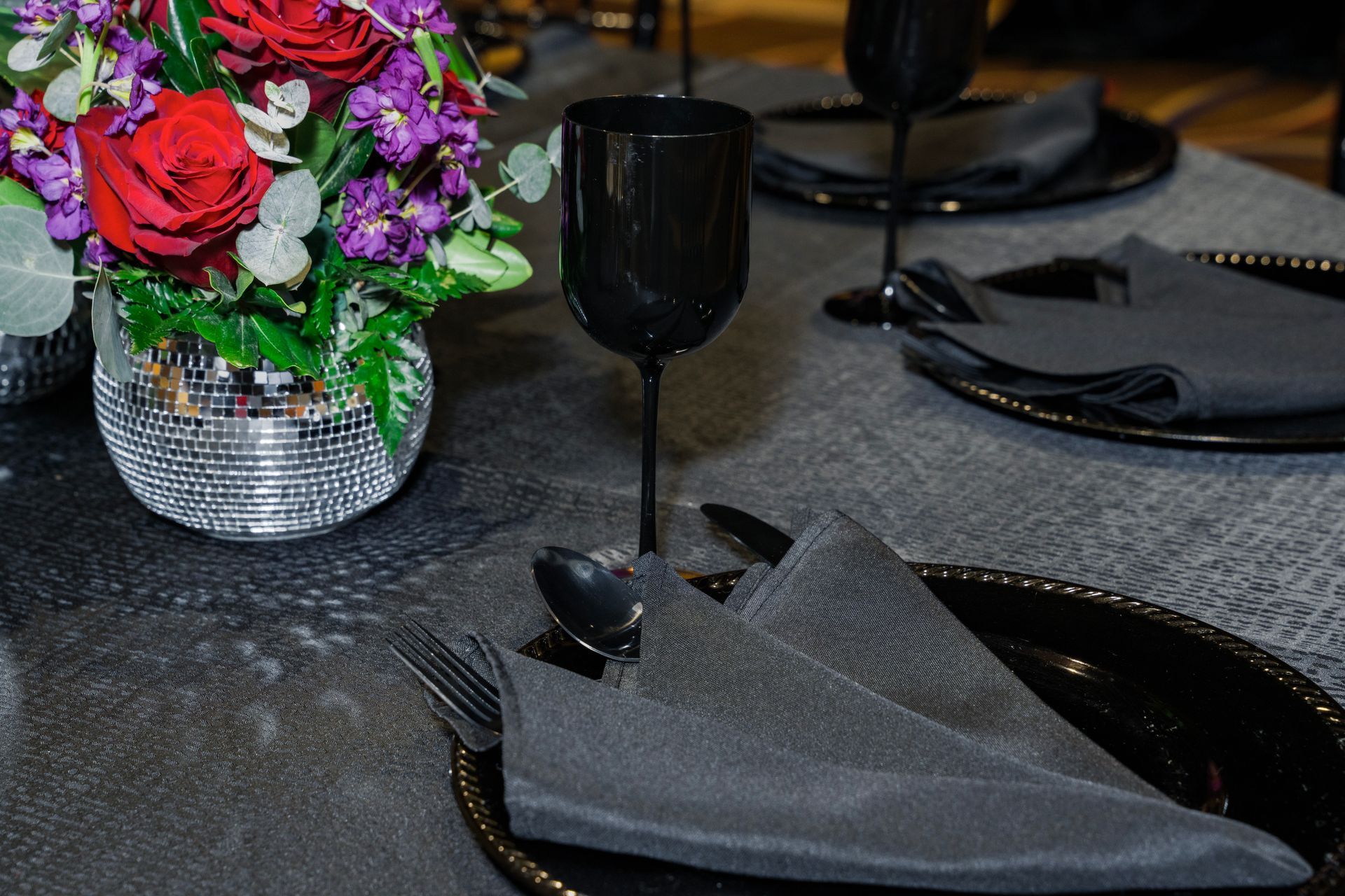 A table setting with plates , utensils , and a vase of flowers.