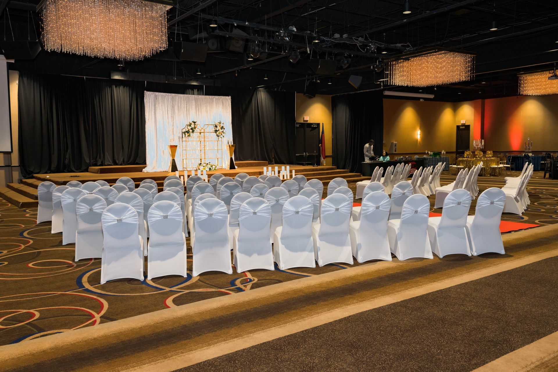 A large room filled with white chairs and a stage.