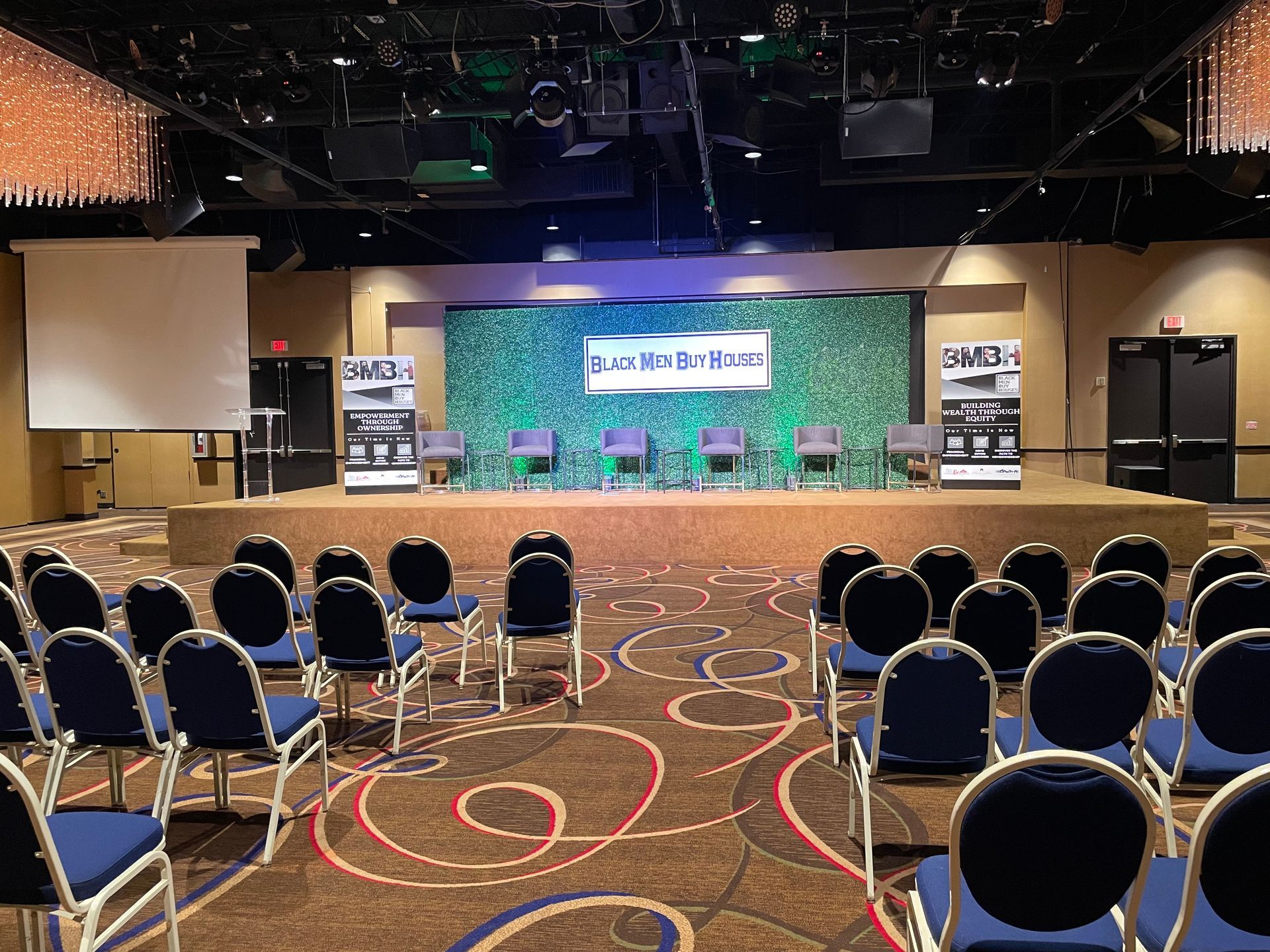 A large room with rows of chairs and a projector screen.