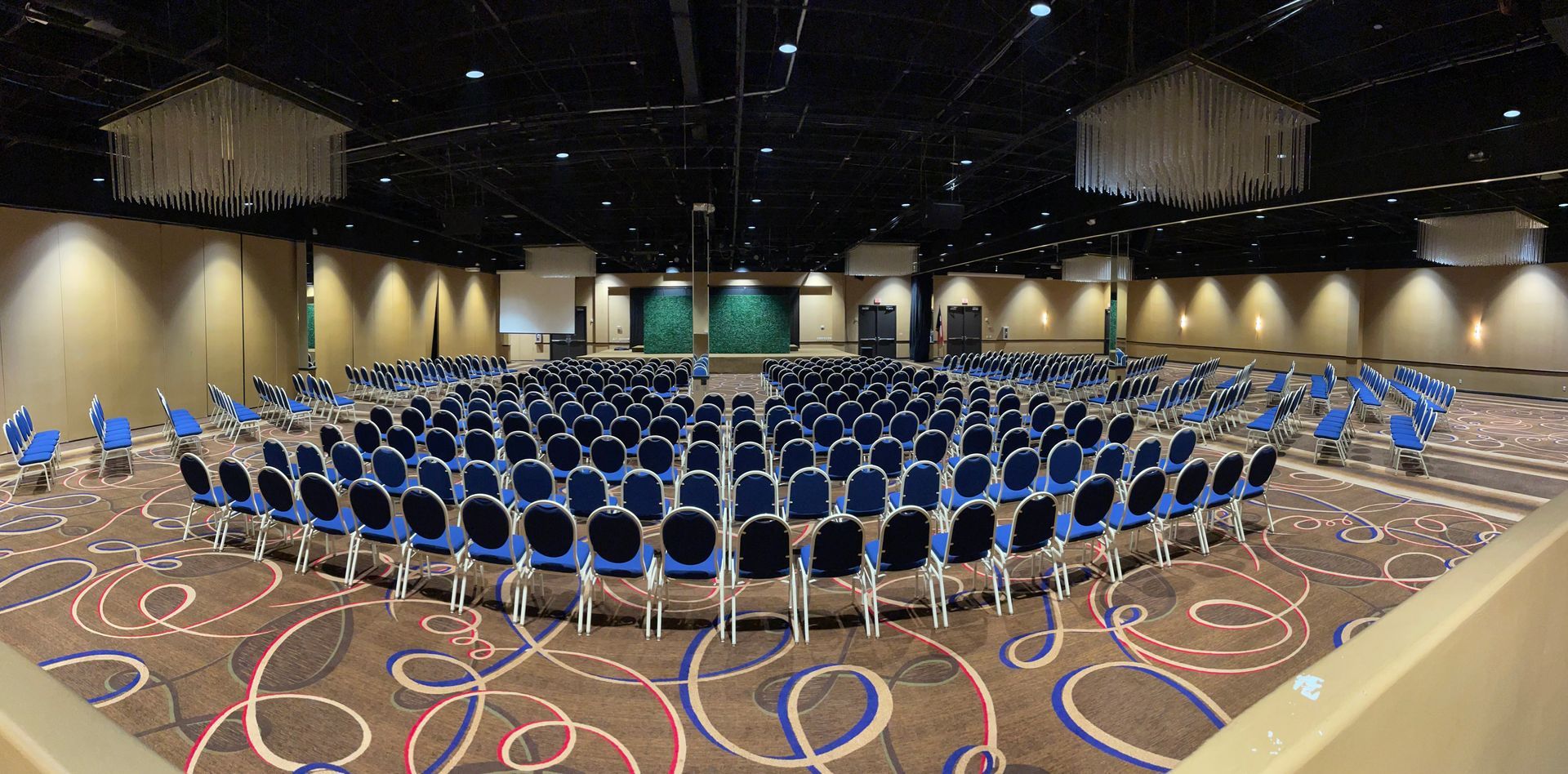 A large auditorium with rows of blue chairs in a circle.
