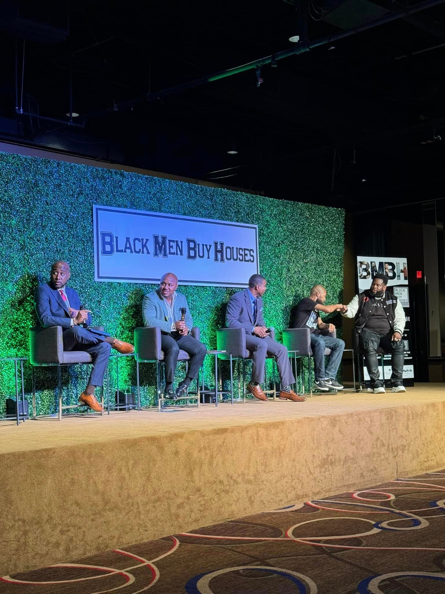 A group of men are sitting on a stage talking to each other.