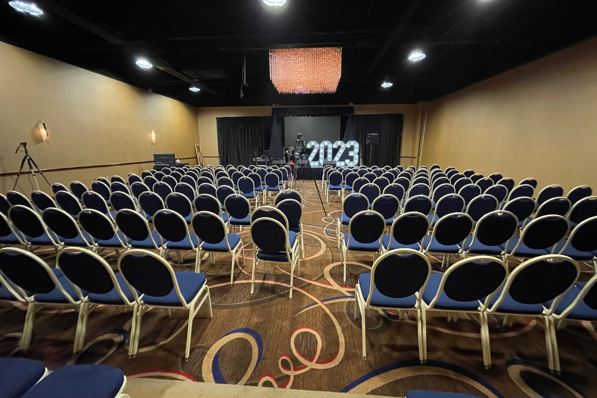 A large auditorium with rows of chairs and a stage with the year 2023 on it.