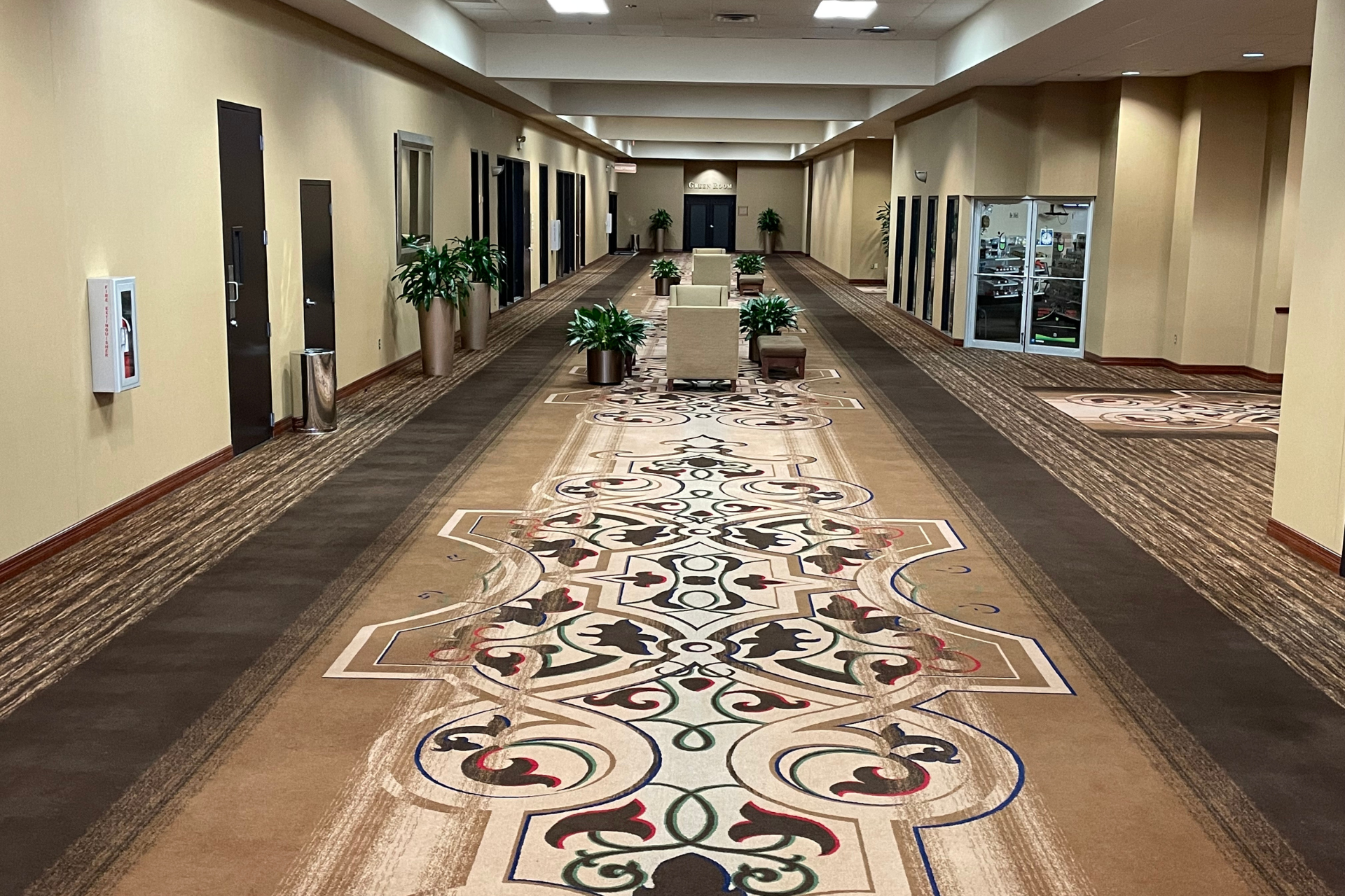 A long hallway with a patterned carpet and chairs