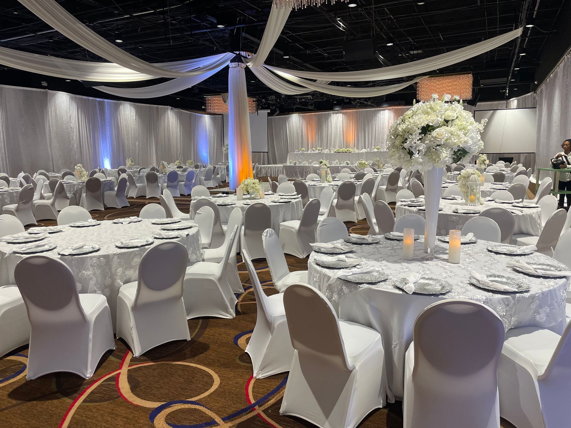 A large room with tables and chairs set up for a wedding reception.