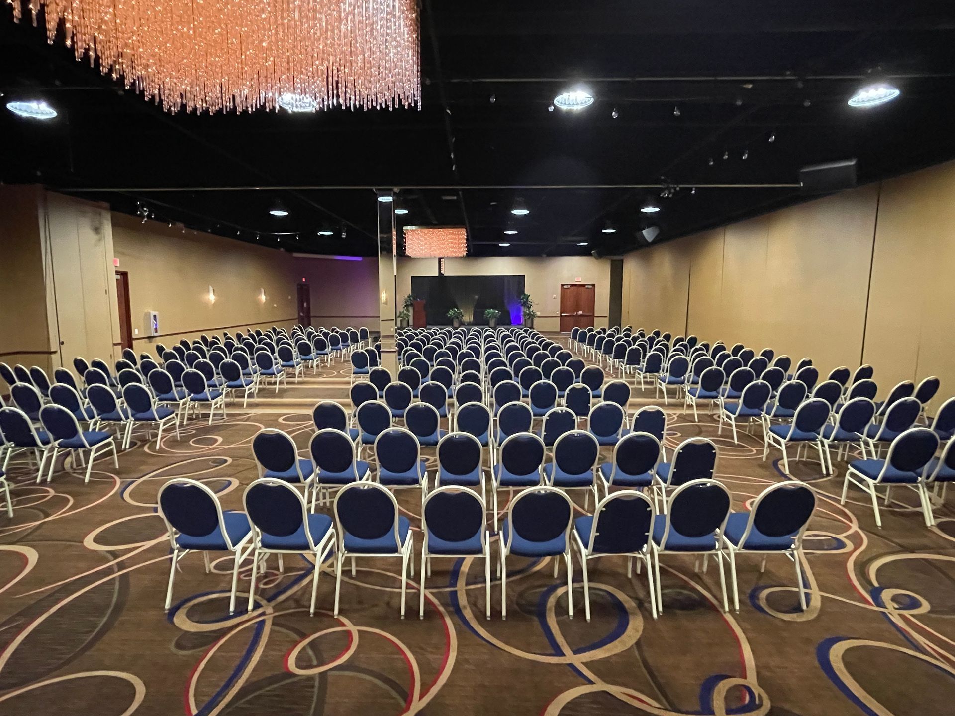 A large conference room with rows of chairs and a chandelier hanging from the ceiling.