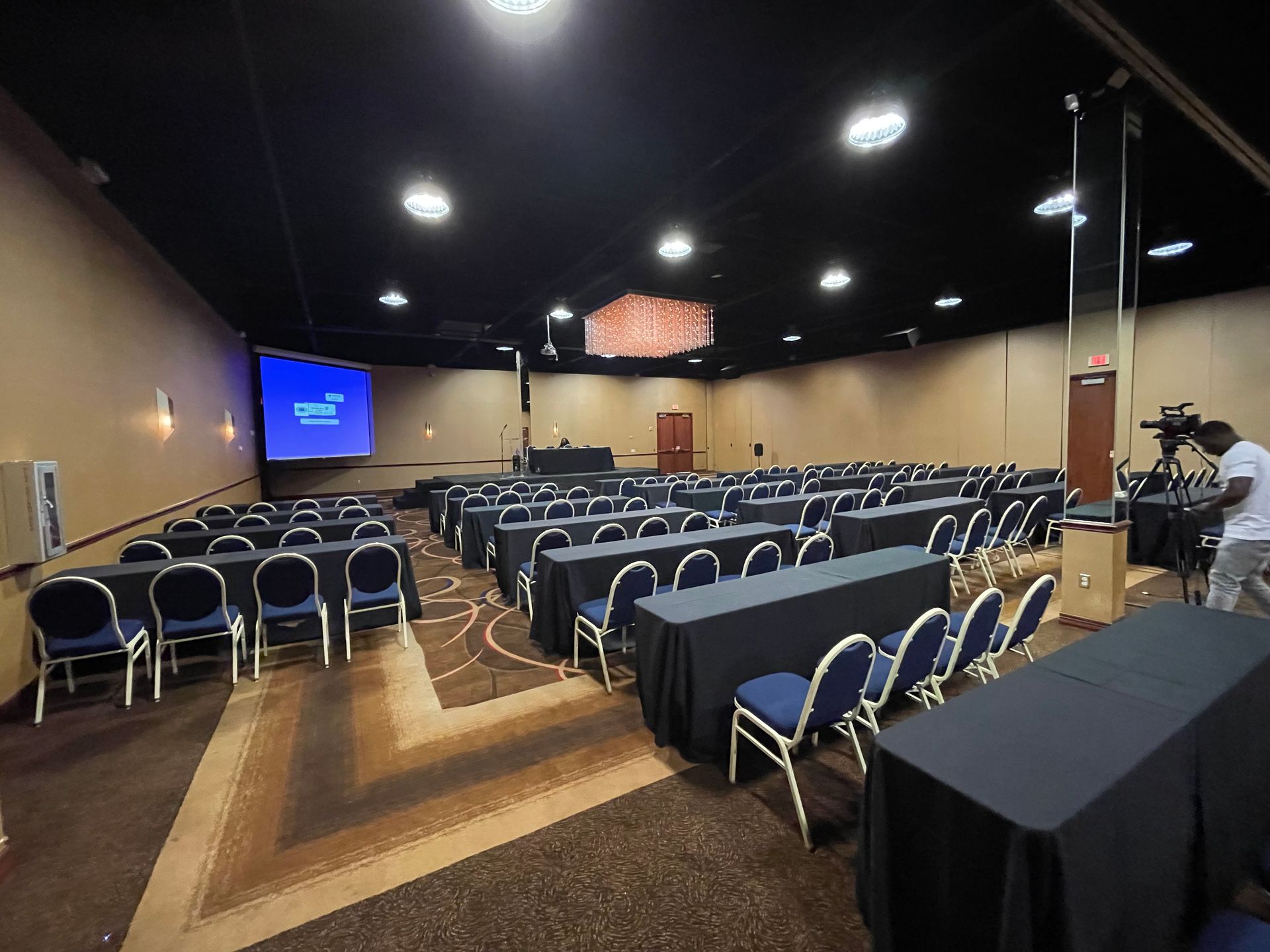 A large conference room with rows of tables and chairs