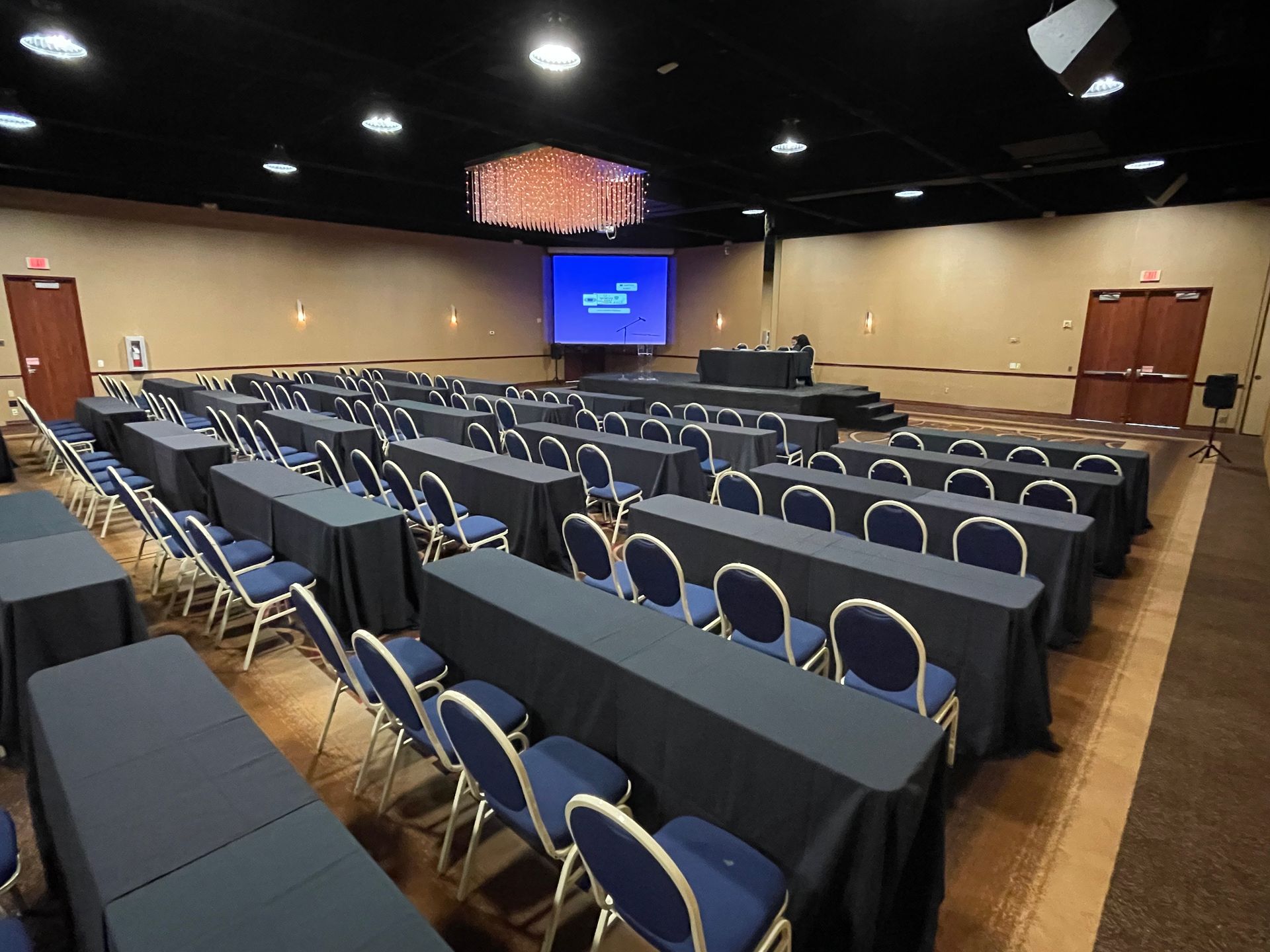 A large conference room with tables and chairs and a projector screen.