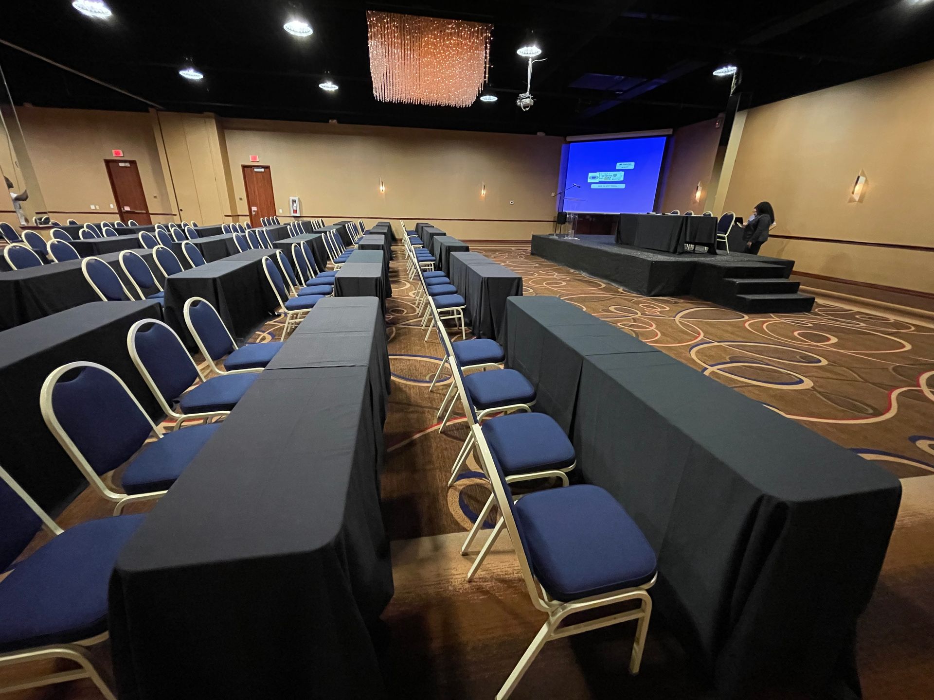 A large conference room with tables and chairs and a projector screen.
