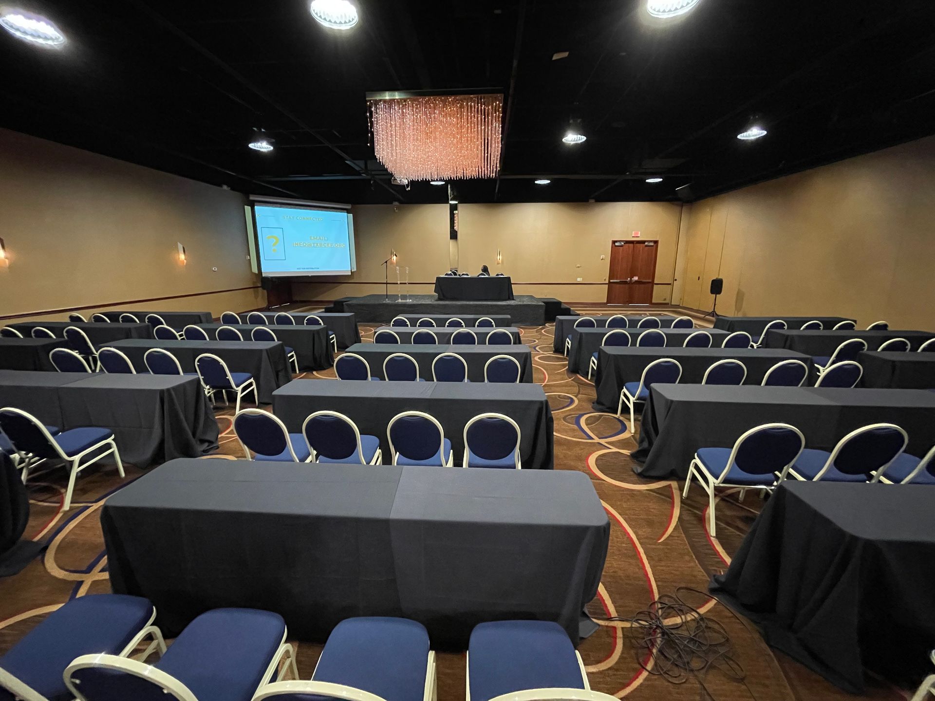 A large conference room with tables and chairs and a projector screen.