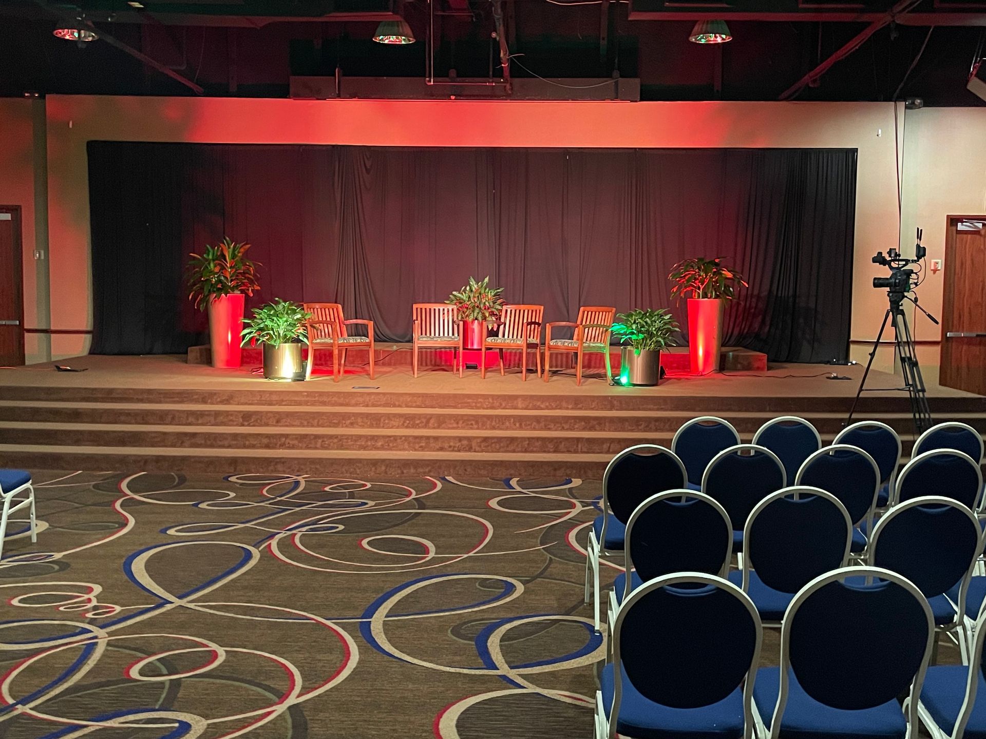 A large room with rows of chairs in front of a stage.