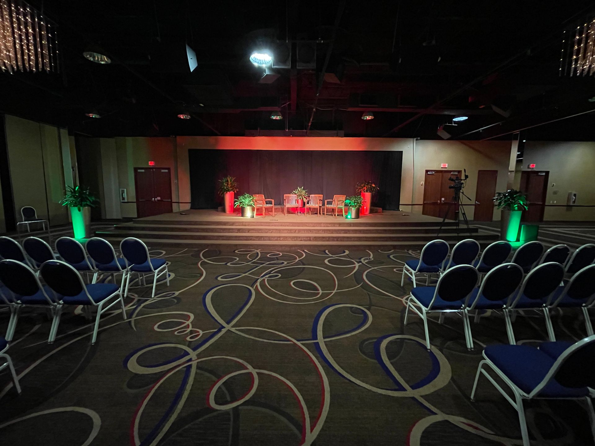 A large room with rows of chairs and a stage in the middle.