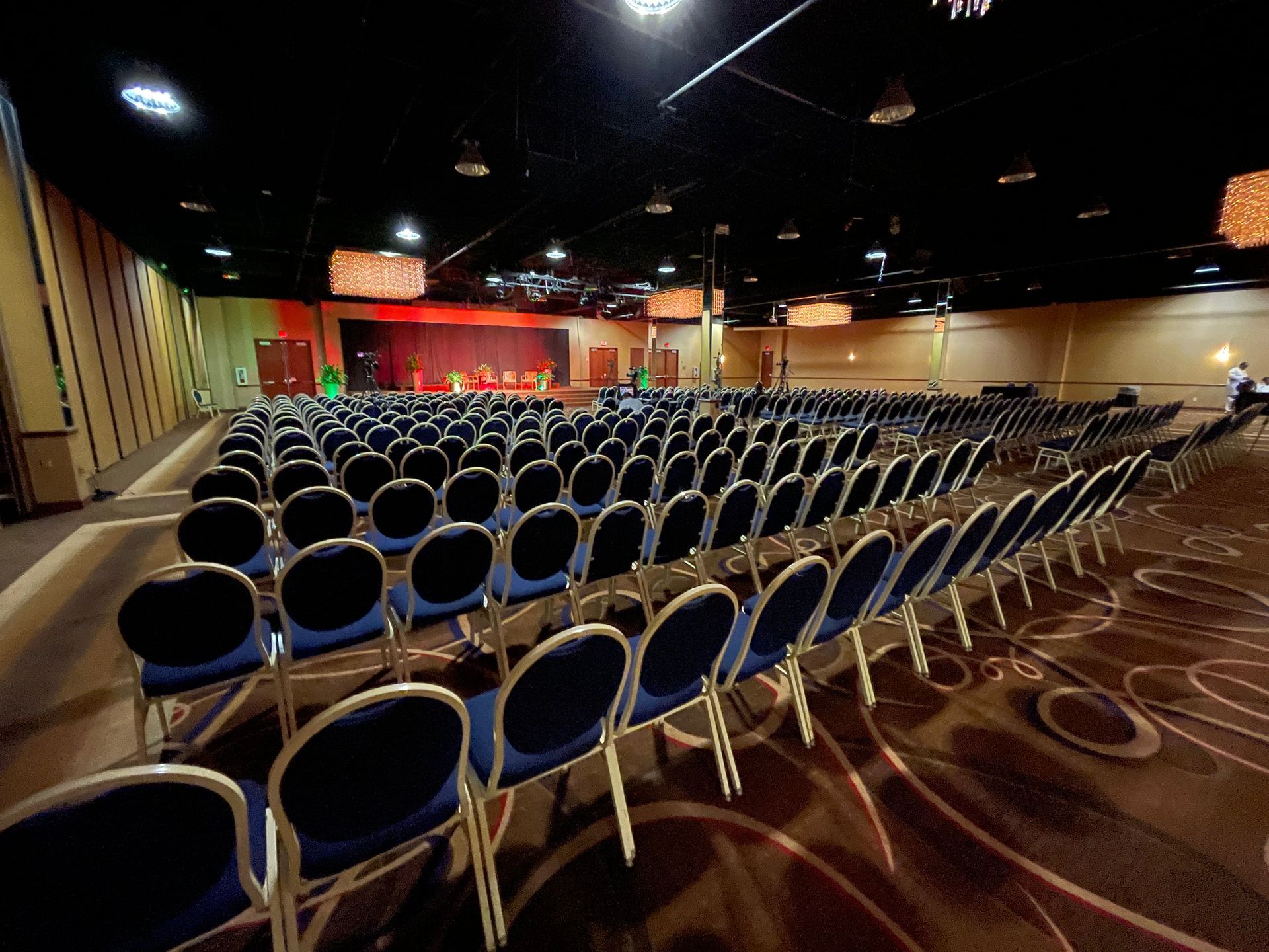 A large auditorium with rows of blue chairs and a stage