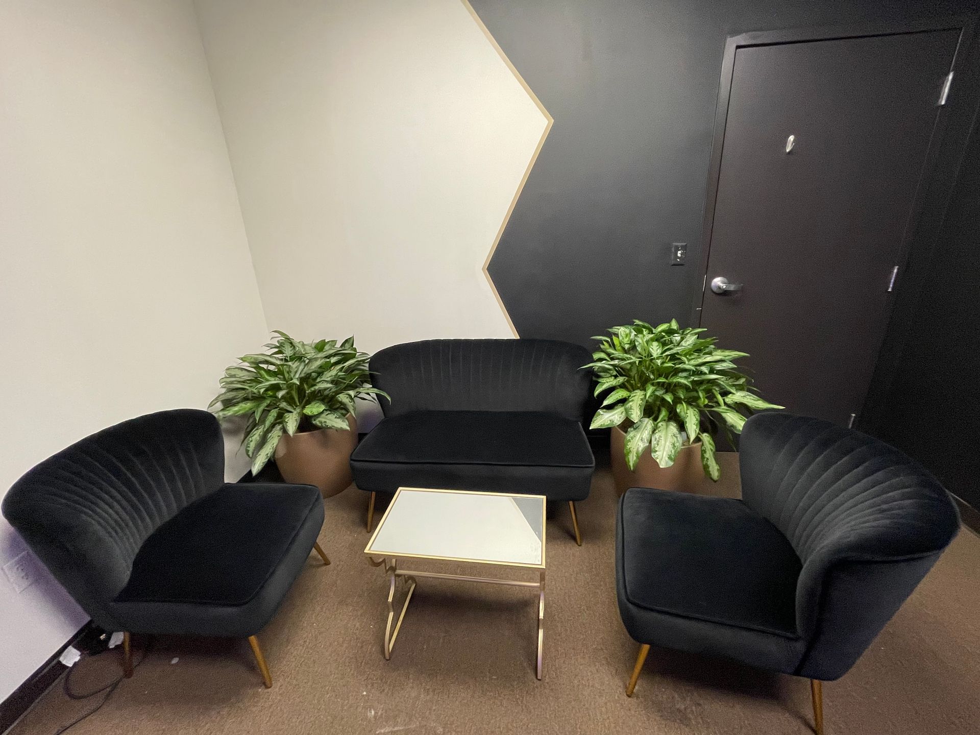 A living room with black chairs , a couch , and a table.