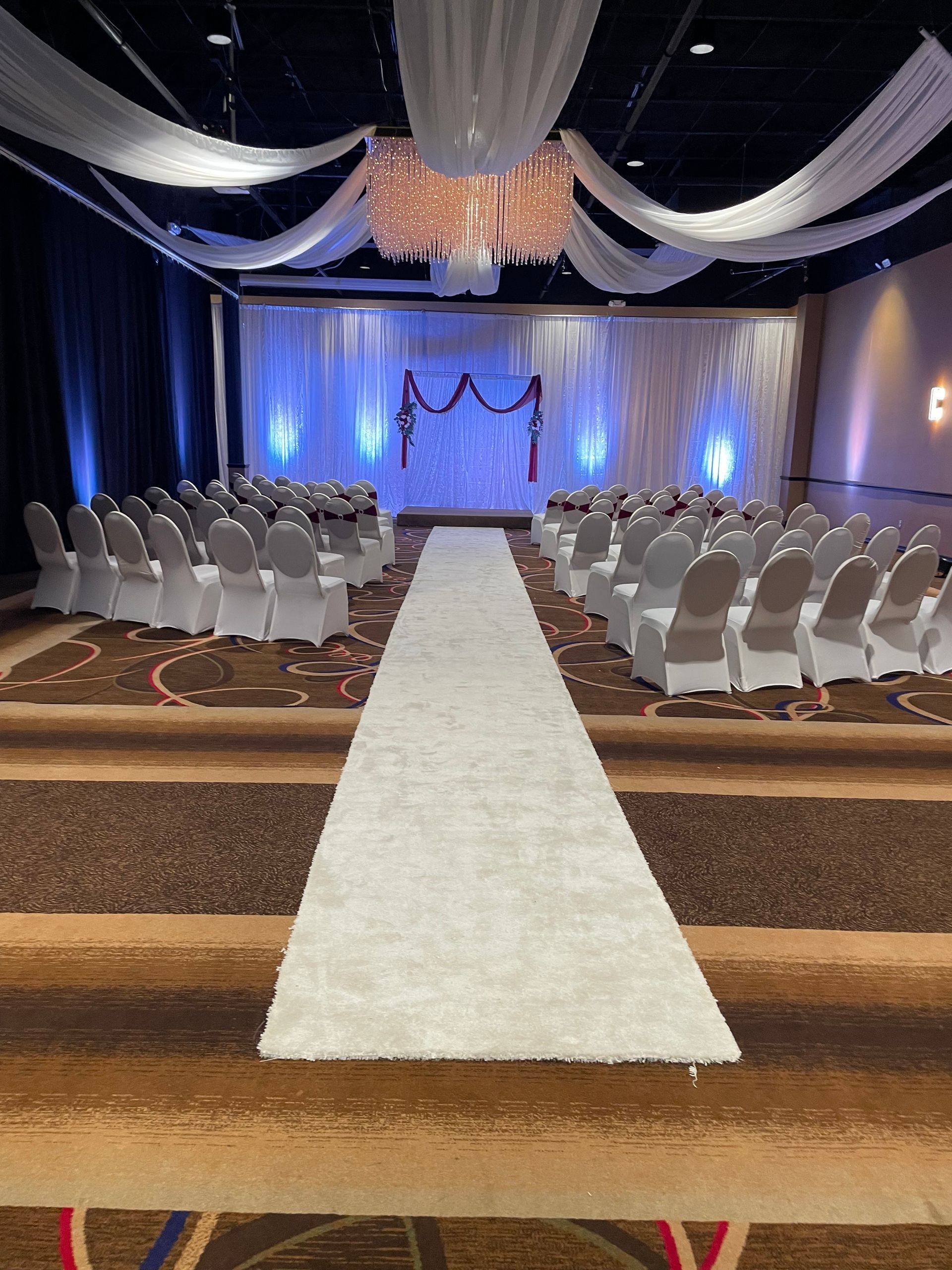 A large room with rows of chairs and a white aisle leading to a stage.