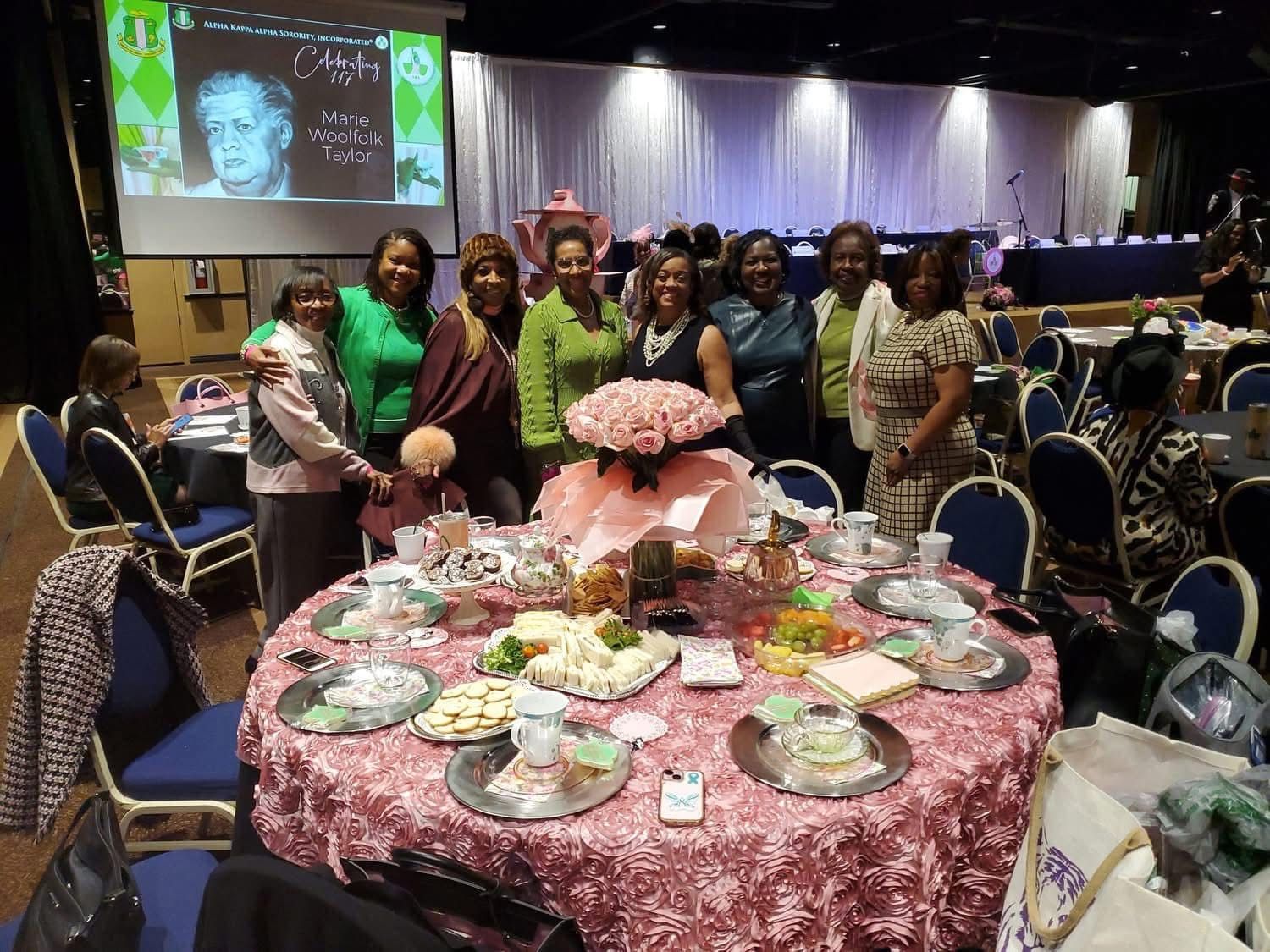A group of women are posing for a picture in front of a table with flowers on it.