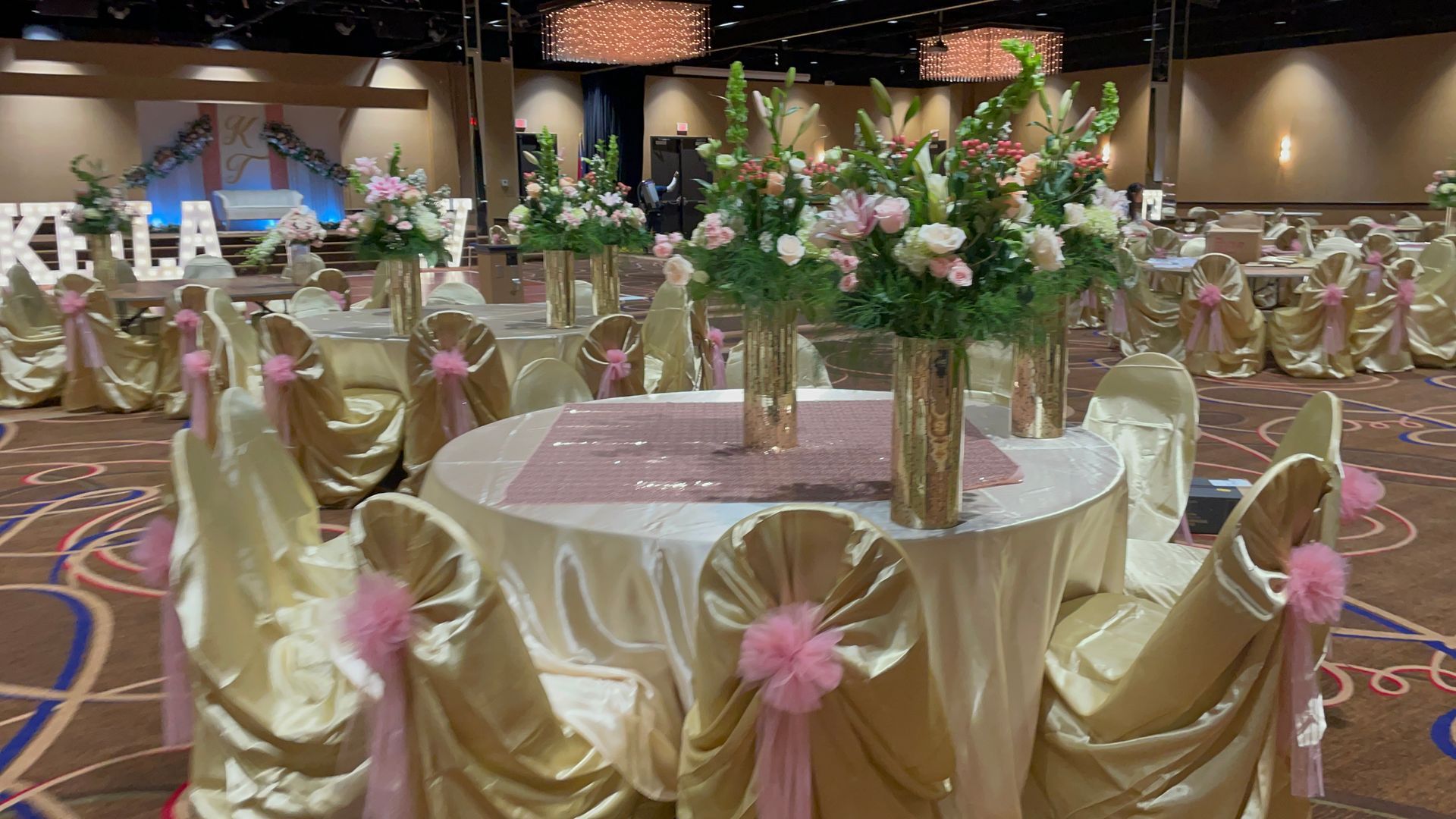 A large room with tables and chairs decorated for a Quinceañera reception.