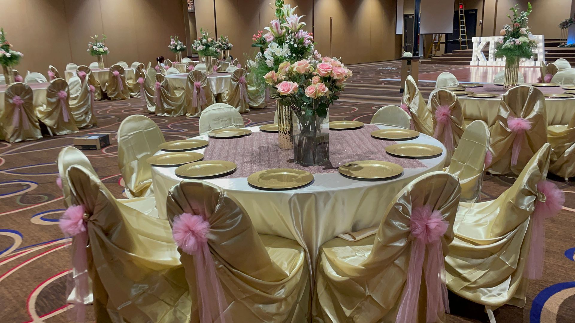 A large room with tables and chairs set up for a Quinceañera event.