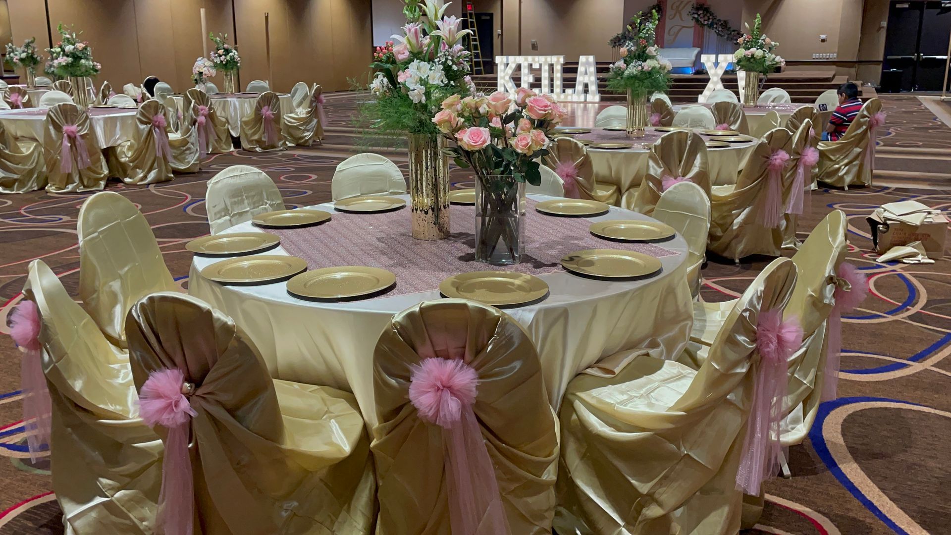 A large room with tables and chairs set up for a Quinceañera event..