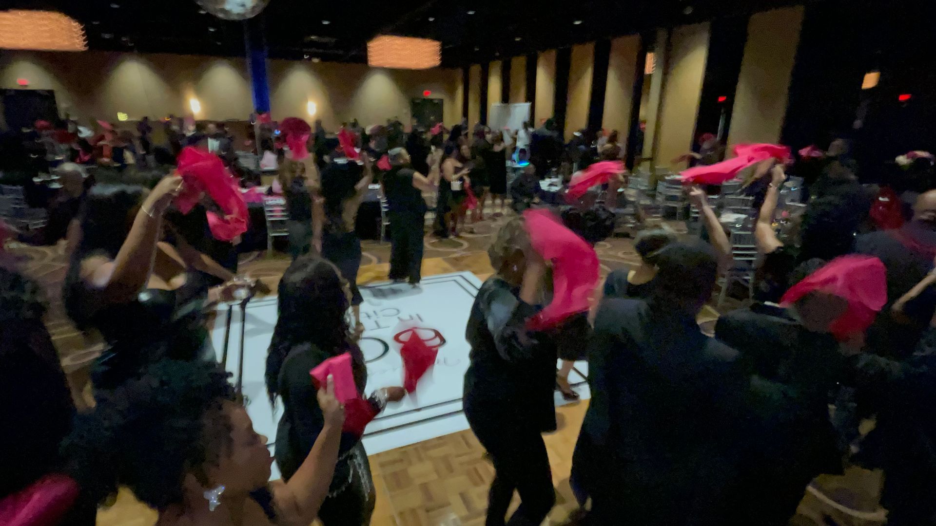 A large group of people are dancing on a dance floor at a party.