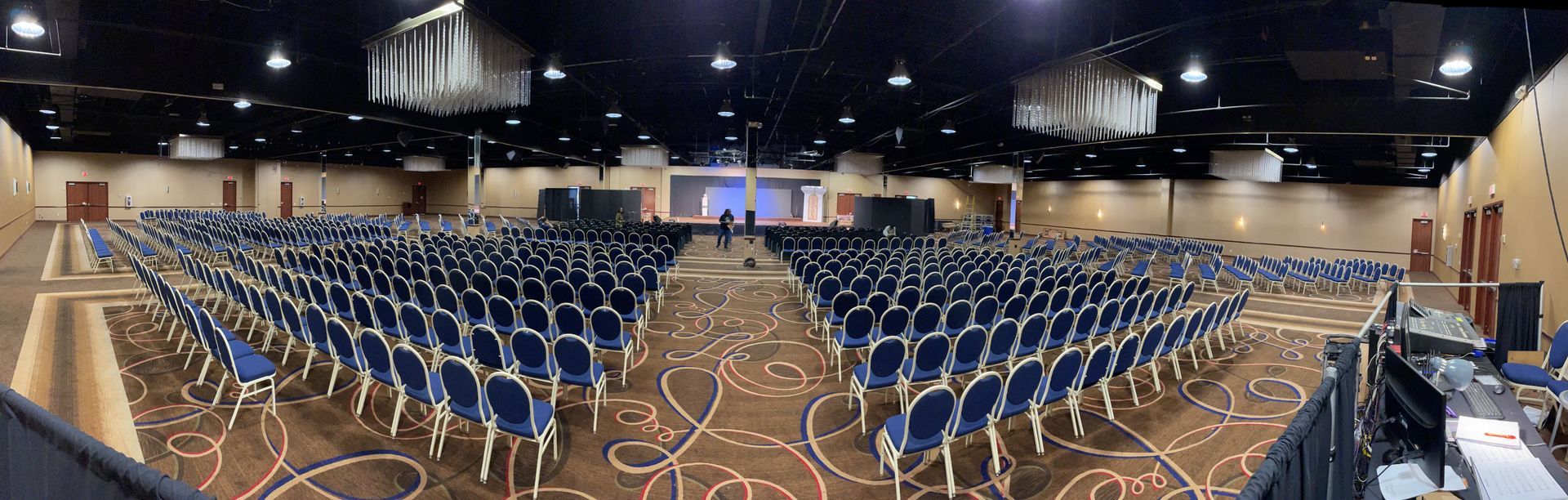 A large auditorium filled with rows of blue chairs and a stage.